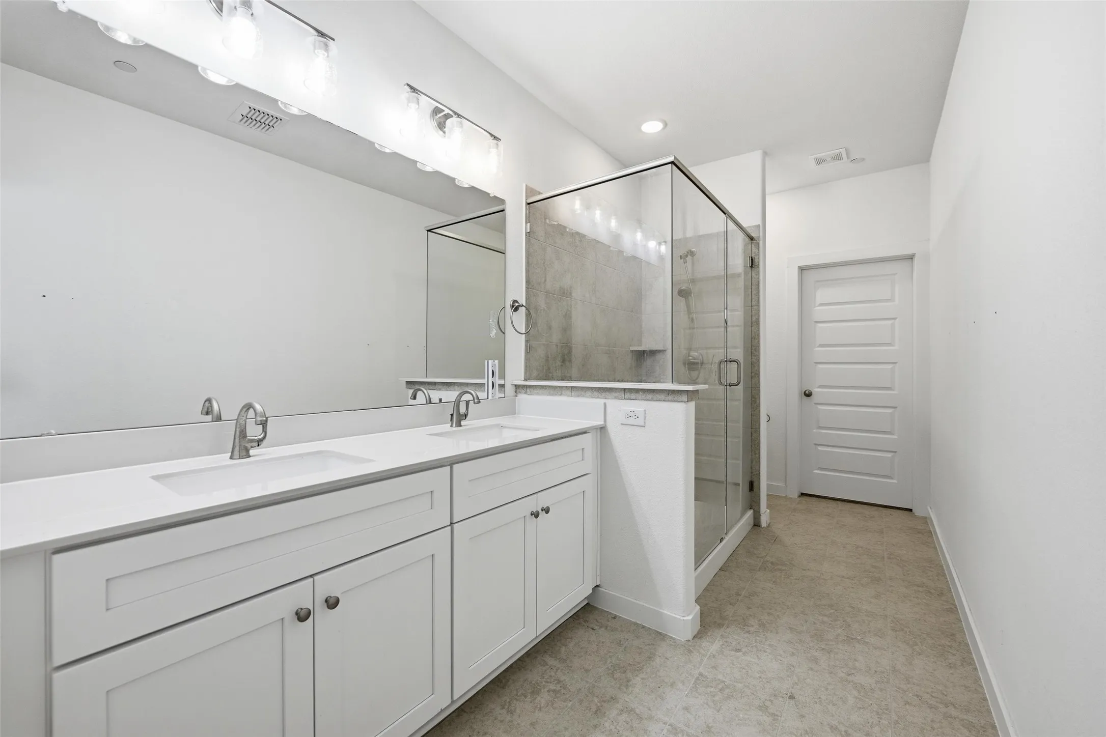 Full bath featuring double vanity and a shower stall