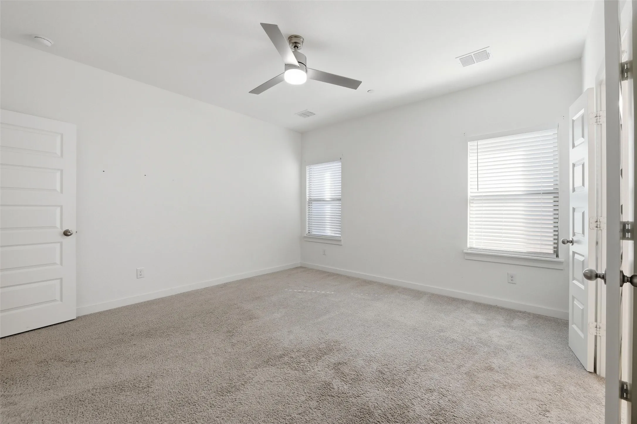 Carpeted spare room with healthy amount of natural light and a ceiling fan