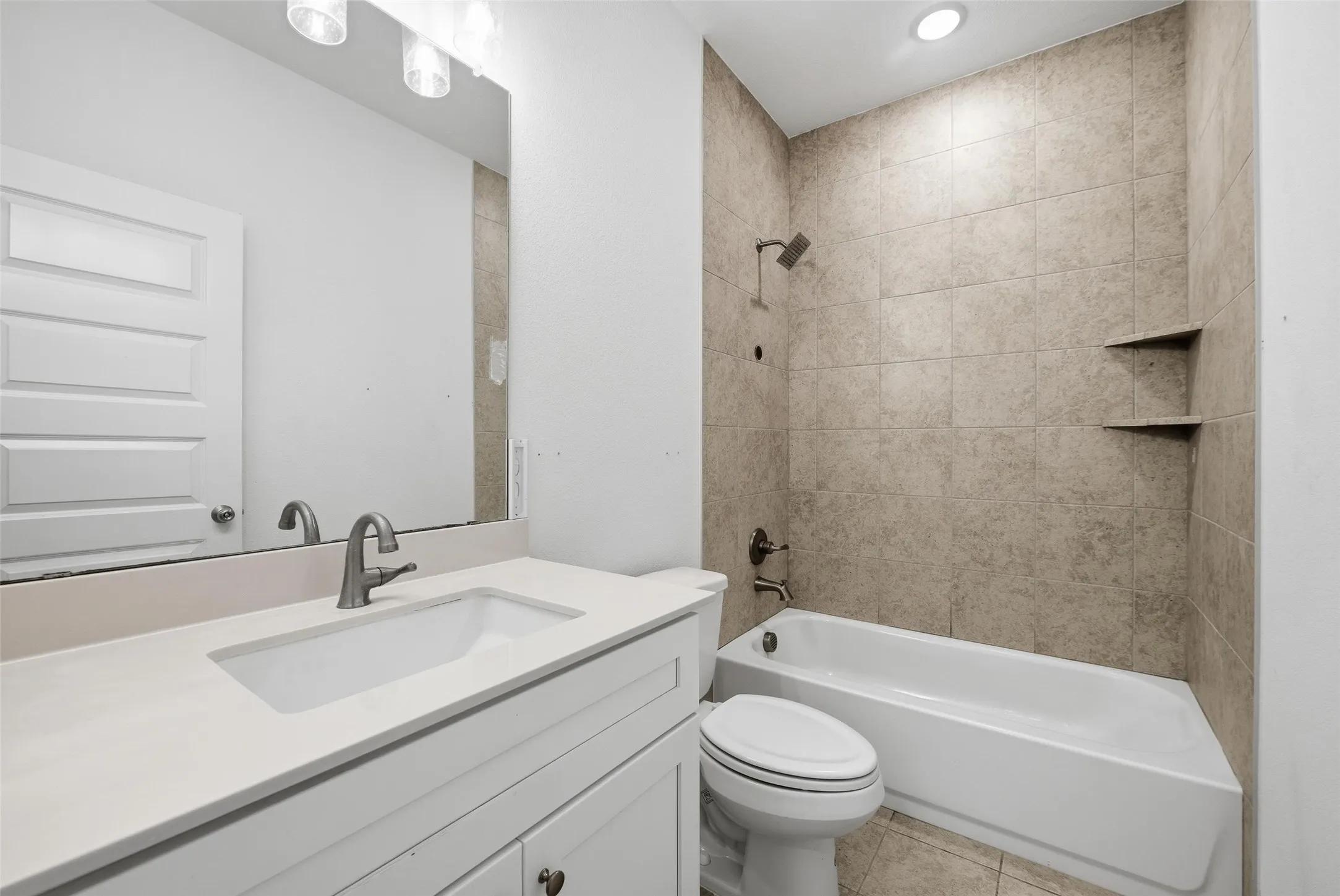 Bathroom with vanity, bathtub / shower combination, light tile patterned floors, and recessed lighting