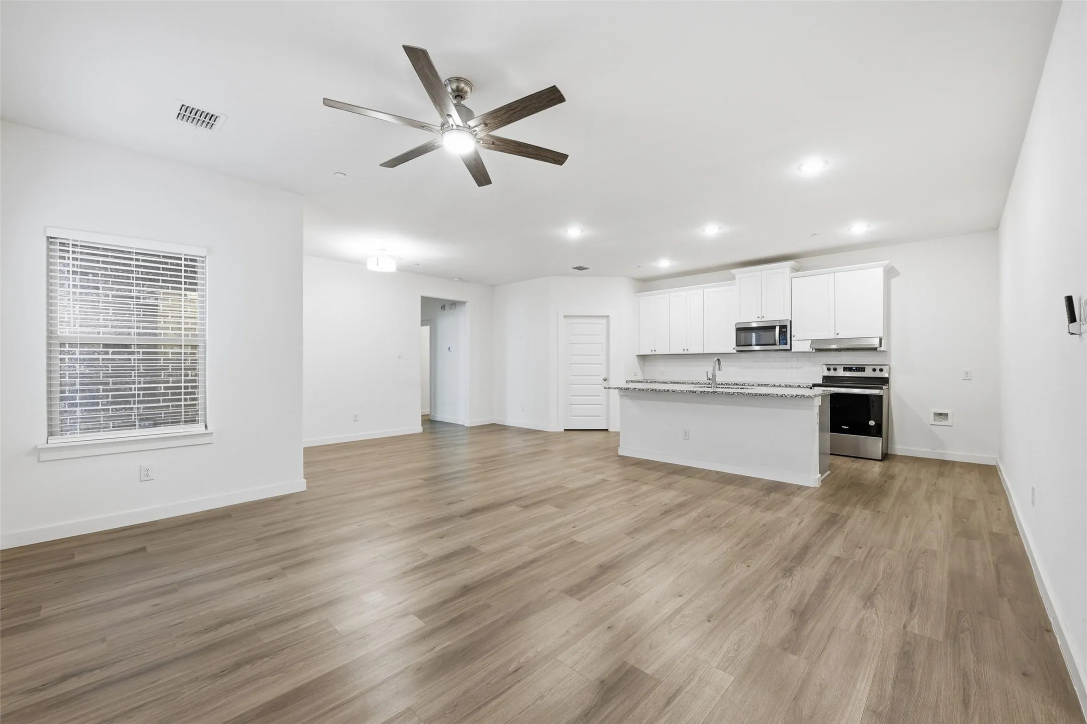 Unfurnished living room featuring a ceiling fan, light wood-type flooring, and recessed lighting