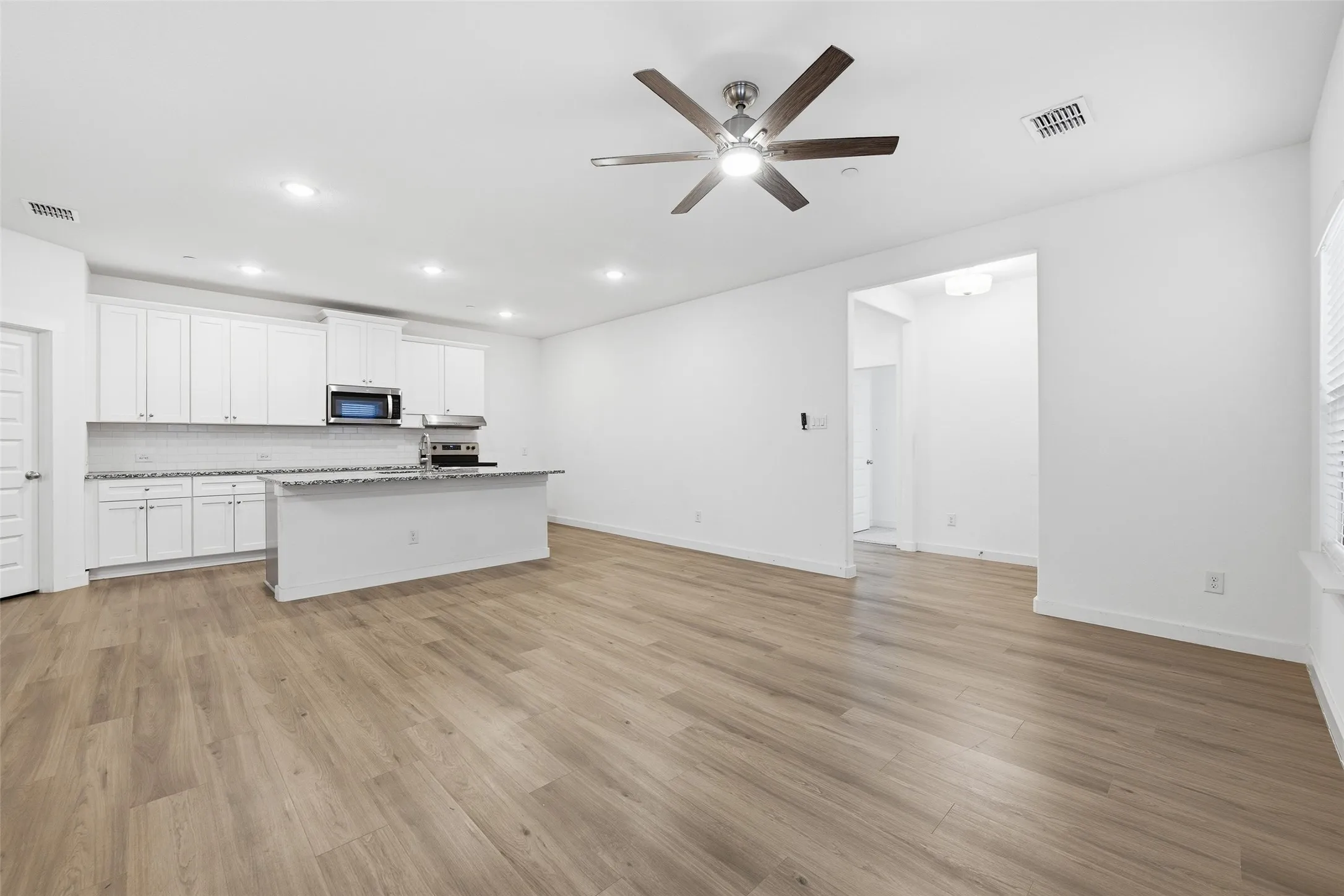 Kitchen with white cabinetry, recessed lighting, ceiling fan, a center island with sink, and open floor plan
