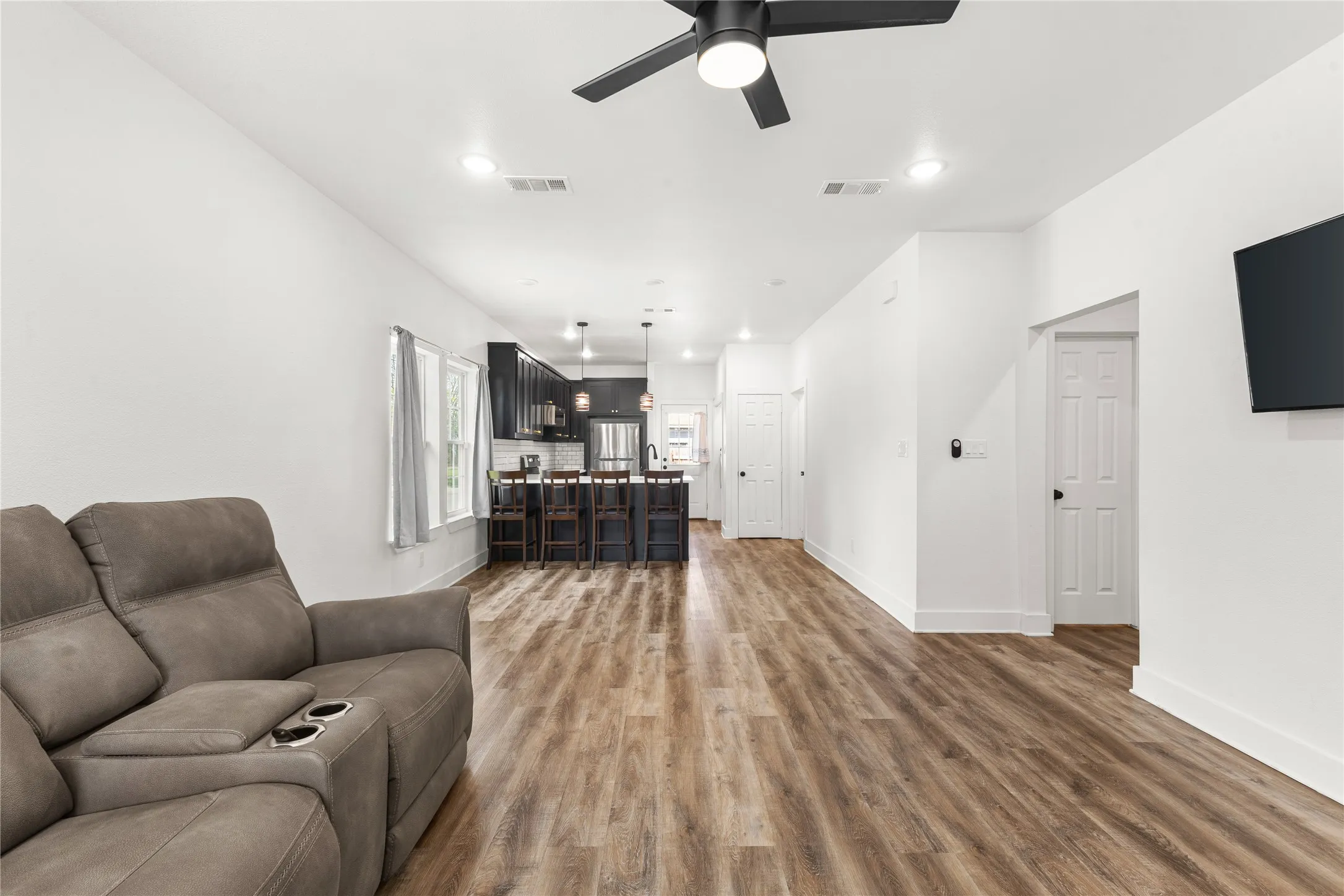 Living area featuring light wood-style floors, ceiling fan, and recessed lighting