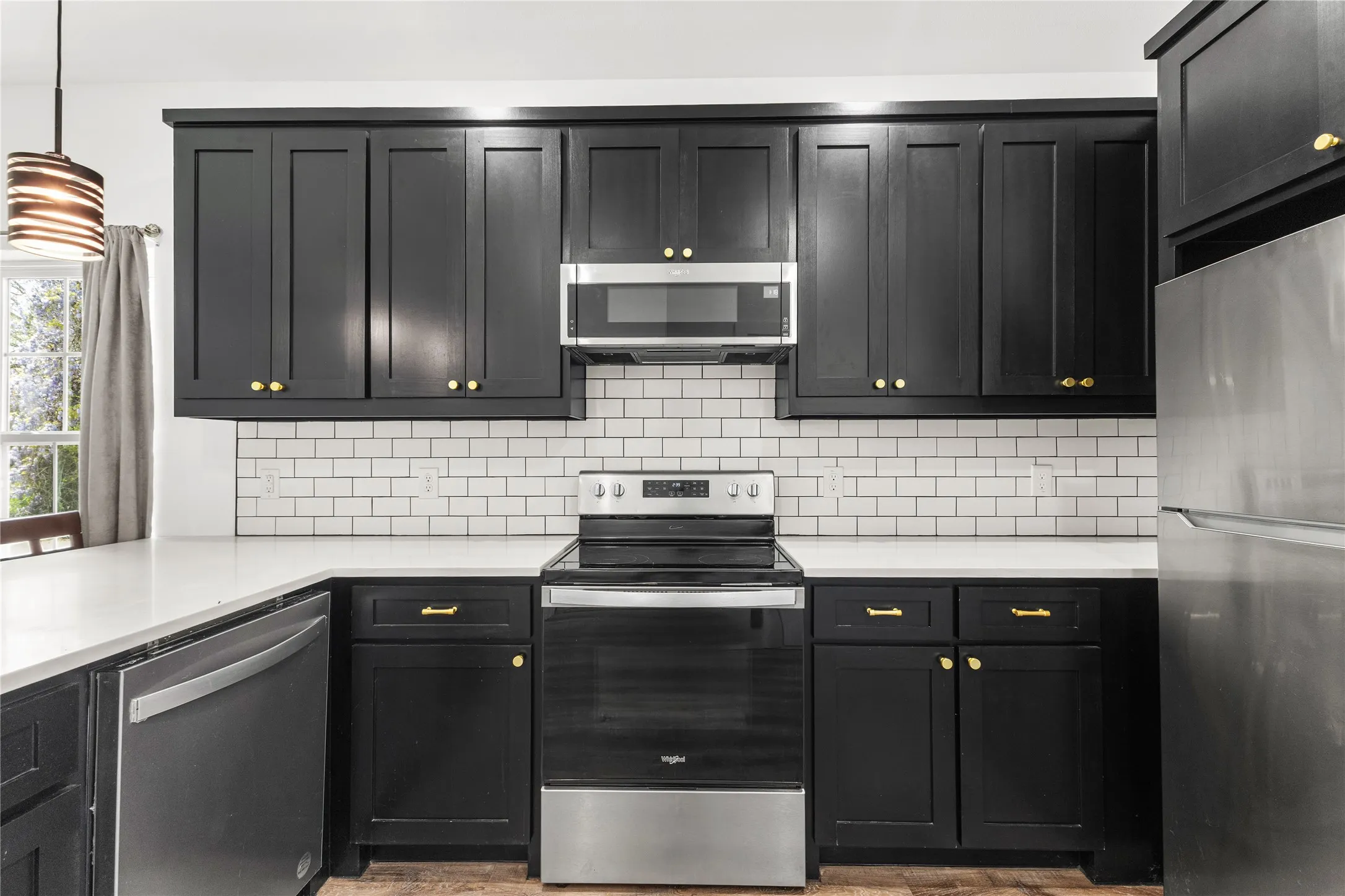 Kitchen featuring stainless steel appliances, tasteful backsplash, and dark cabinets