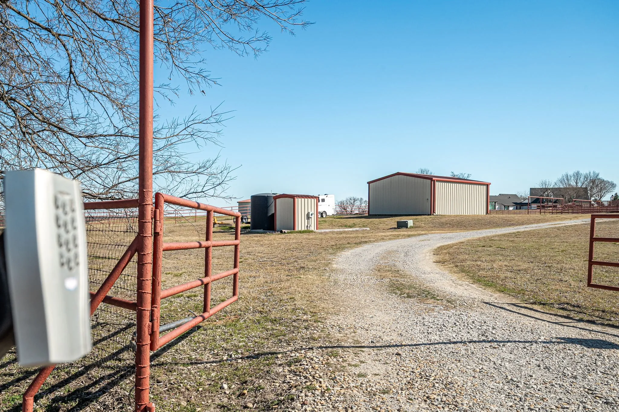 View of dirt / gravel road featuring a gated entry and a pole building