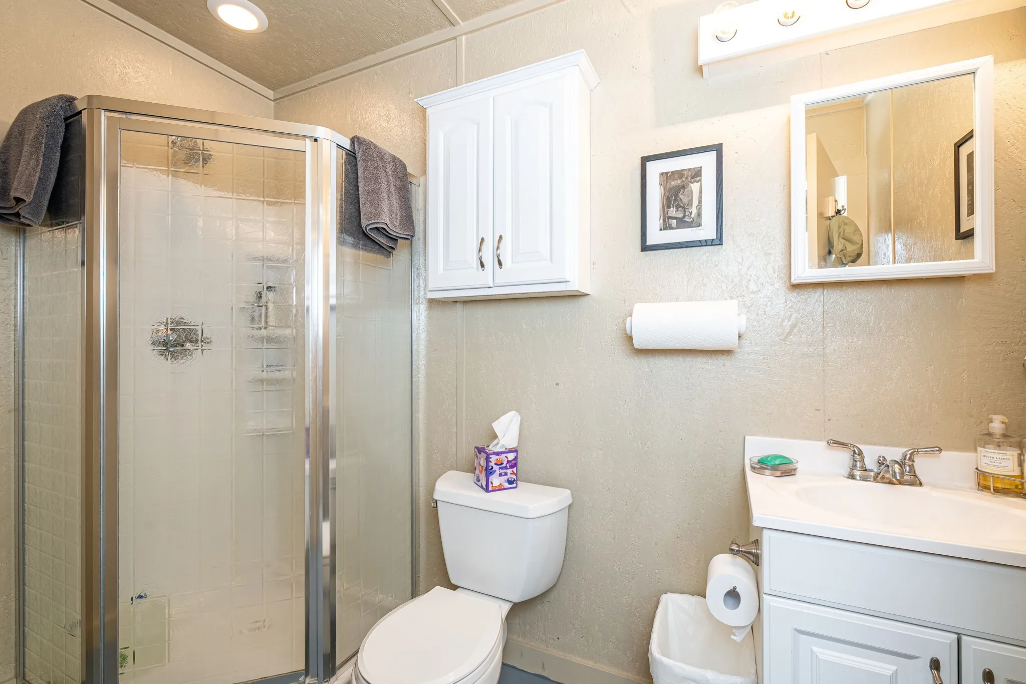Full bath featuring a textured wall, vanity, and a shower stall
