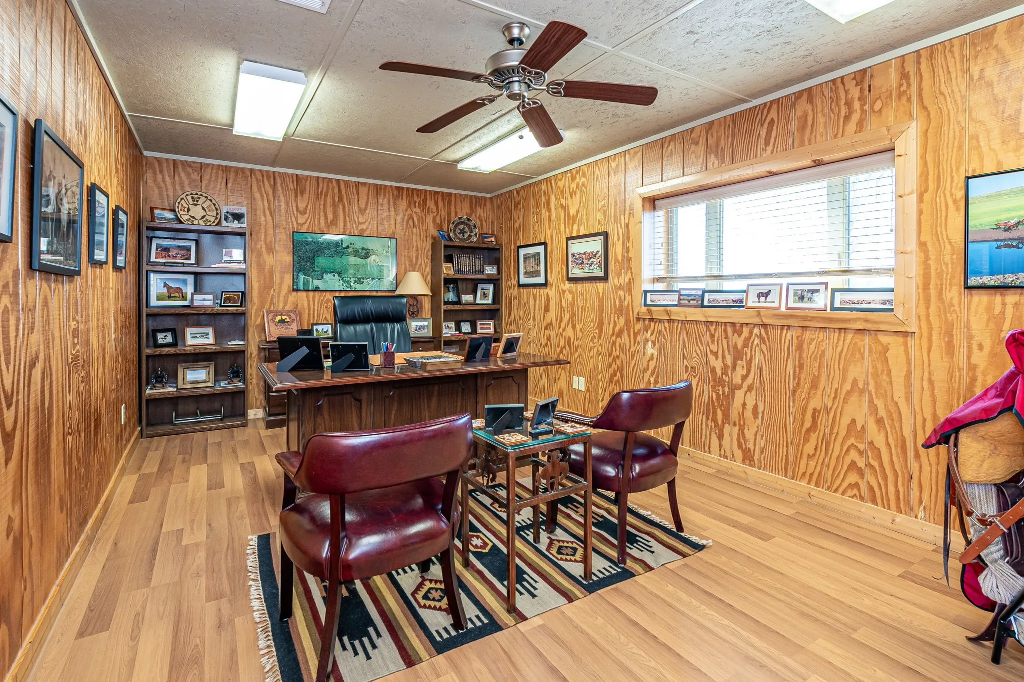 Office space with ceiling fan, wood walls, and light wood-style floors