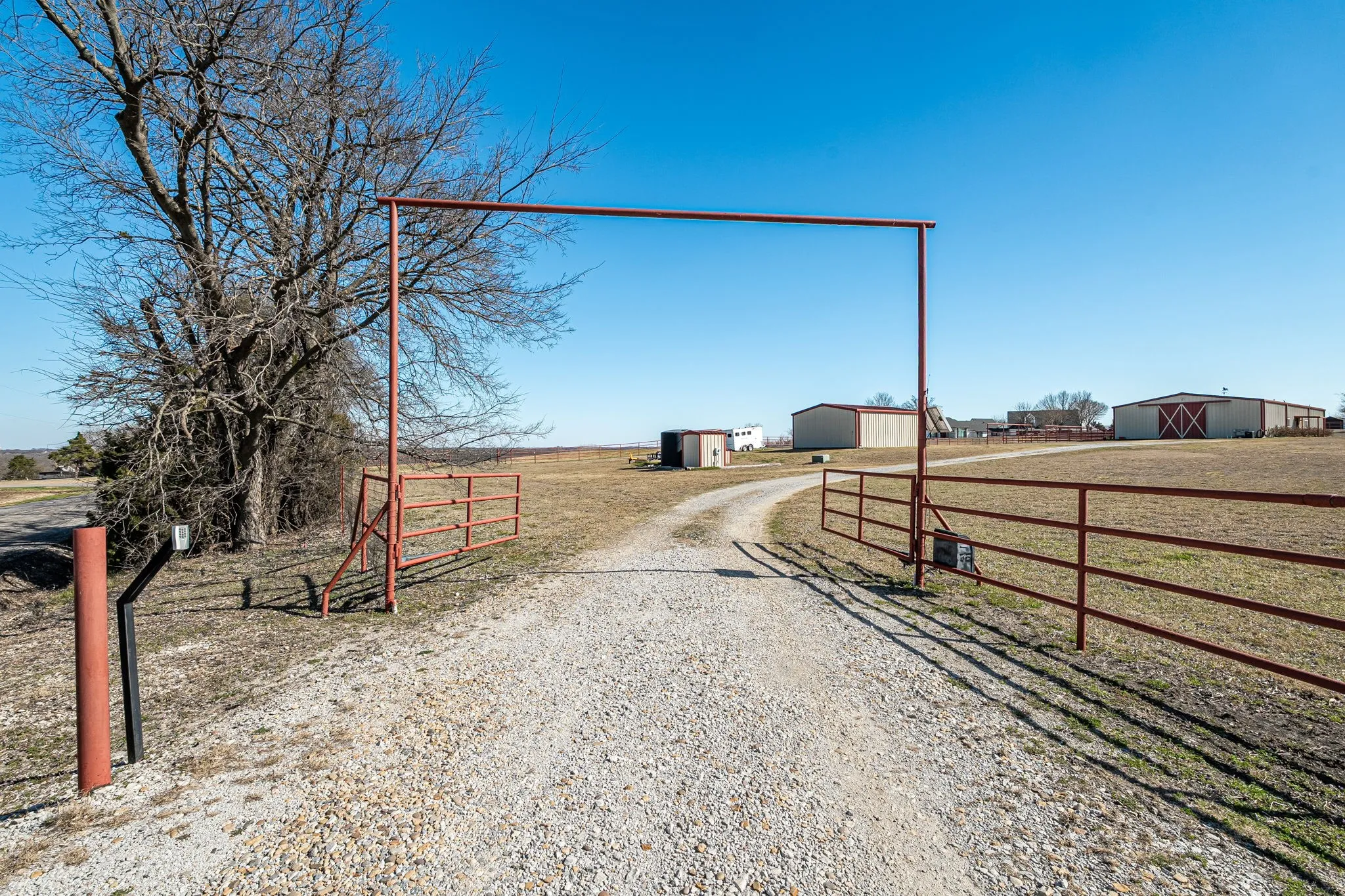 View of dirt / gravel road with a view of rural / pastoral area and a gated entry