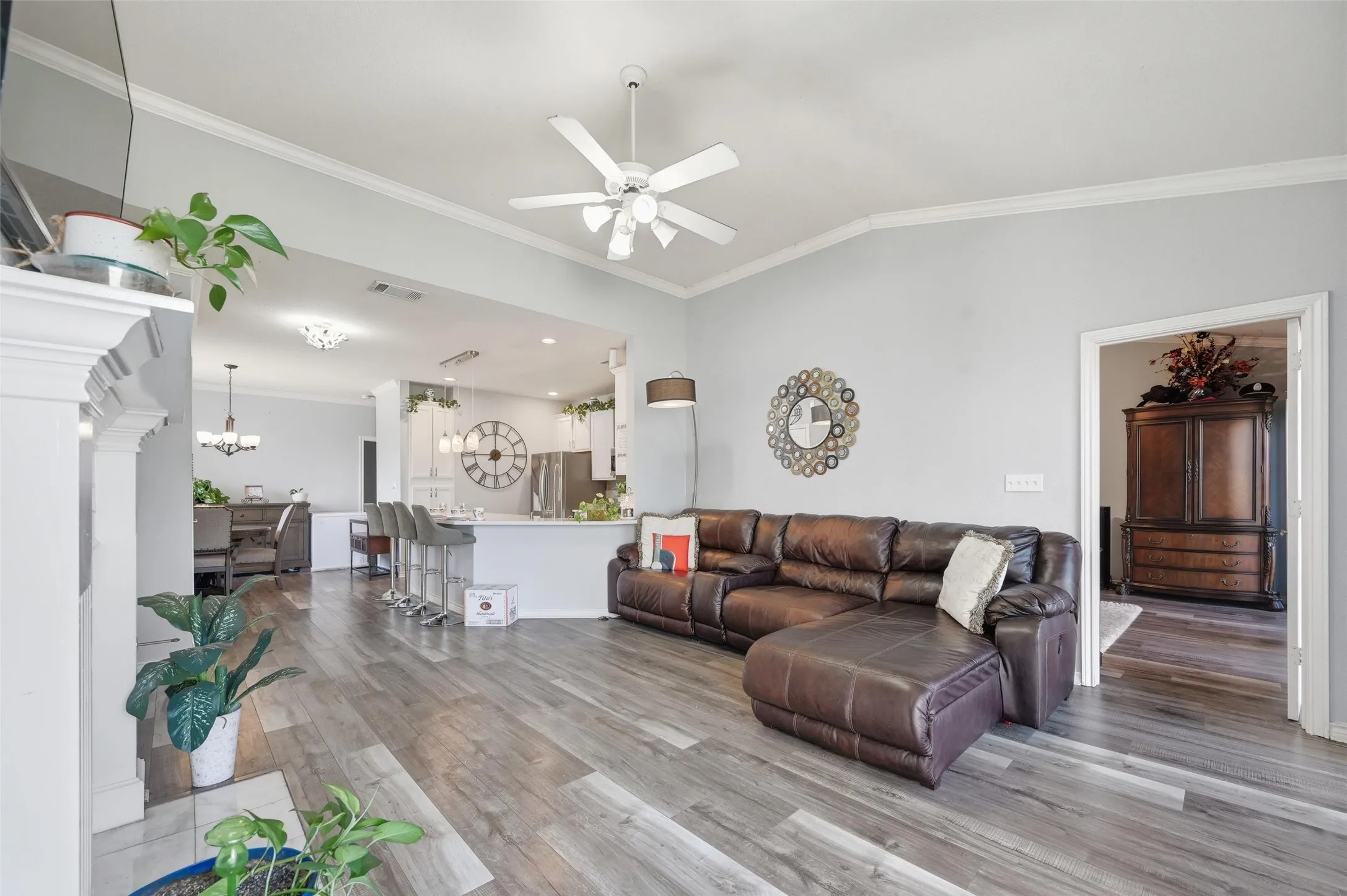 Living room with ornamental molding, vaulted ceiling, light wood-style flooring, a ceiling fan, and a chandelier