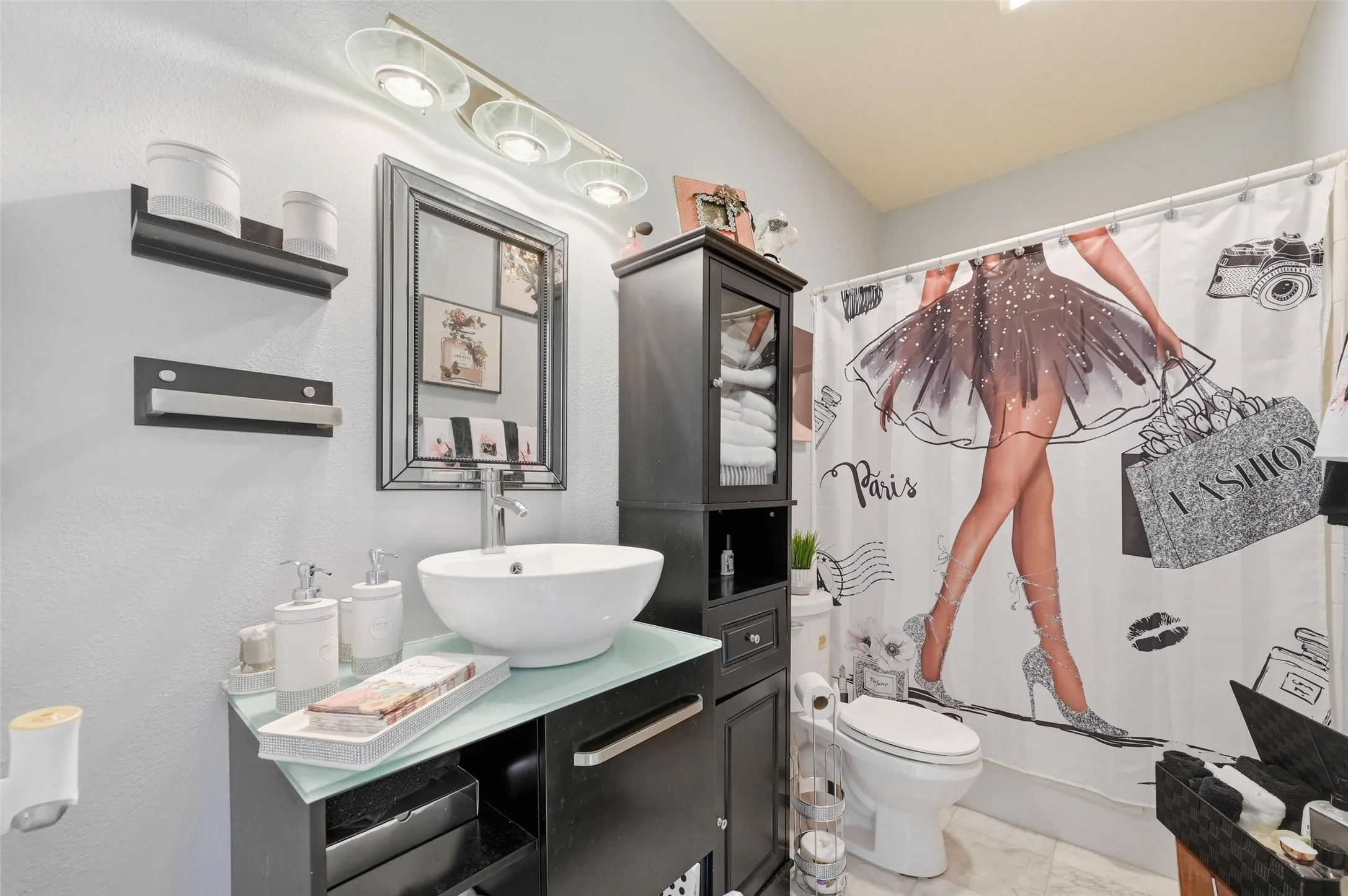 Bathroom with vanity, shower / bath combo with shower curtain, and a textured wall