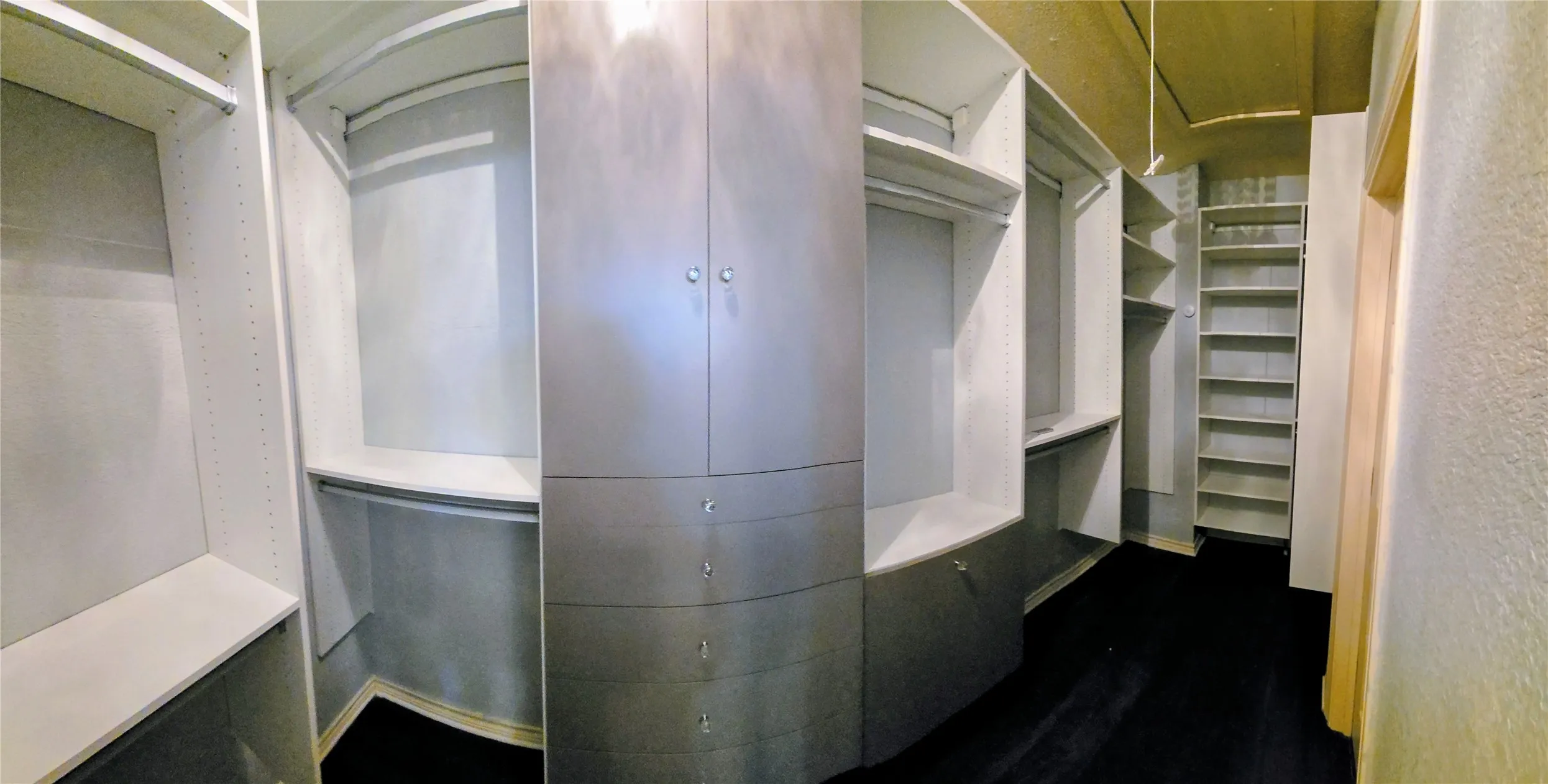 Custom closet system with white shelving, hanging rods, and a curved cabinet unit featuring drawers and doors