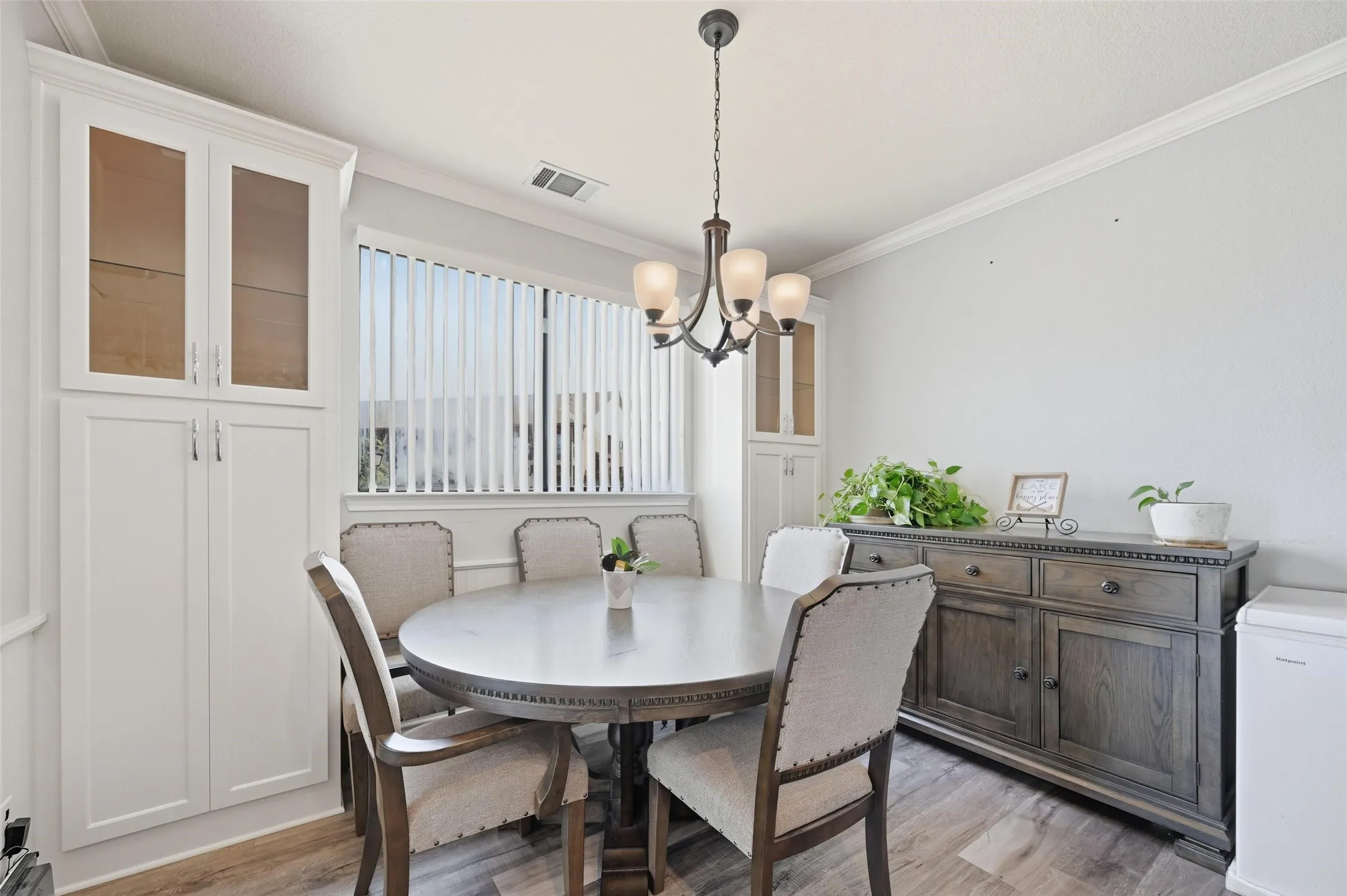 Dining area with crown molding, light wood-style flooring, and a chandelier