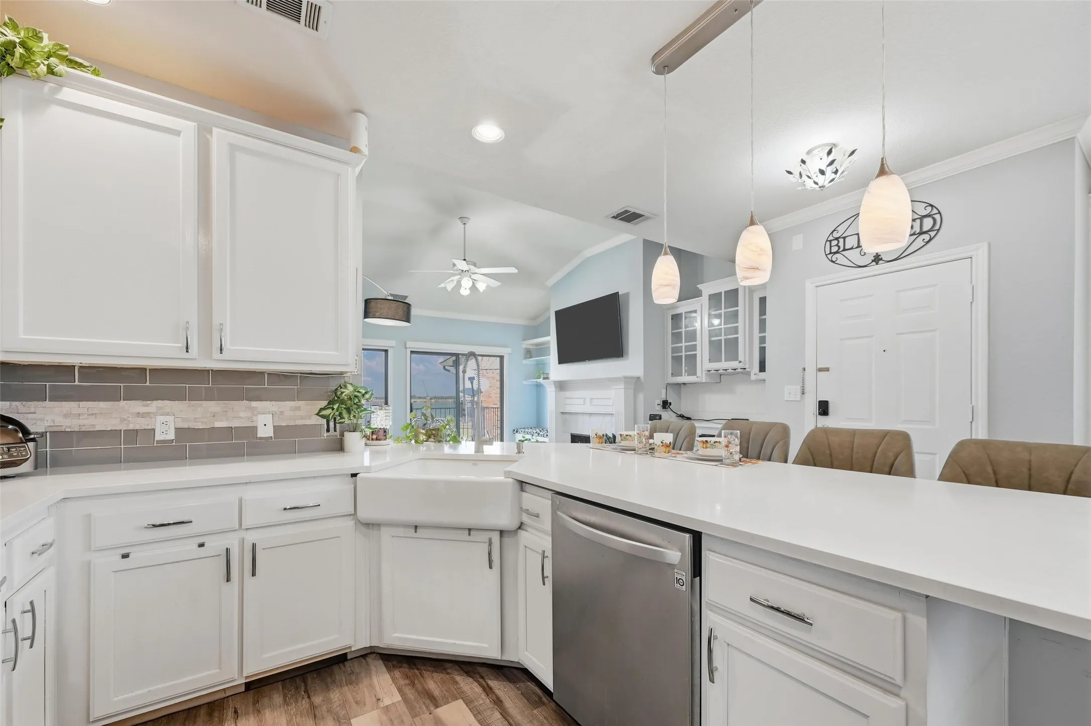 Kitchen with white cabinetry, vaulted ceiling, dishwasher, ornamental molding, and light wood-style flooring