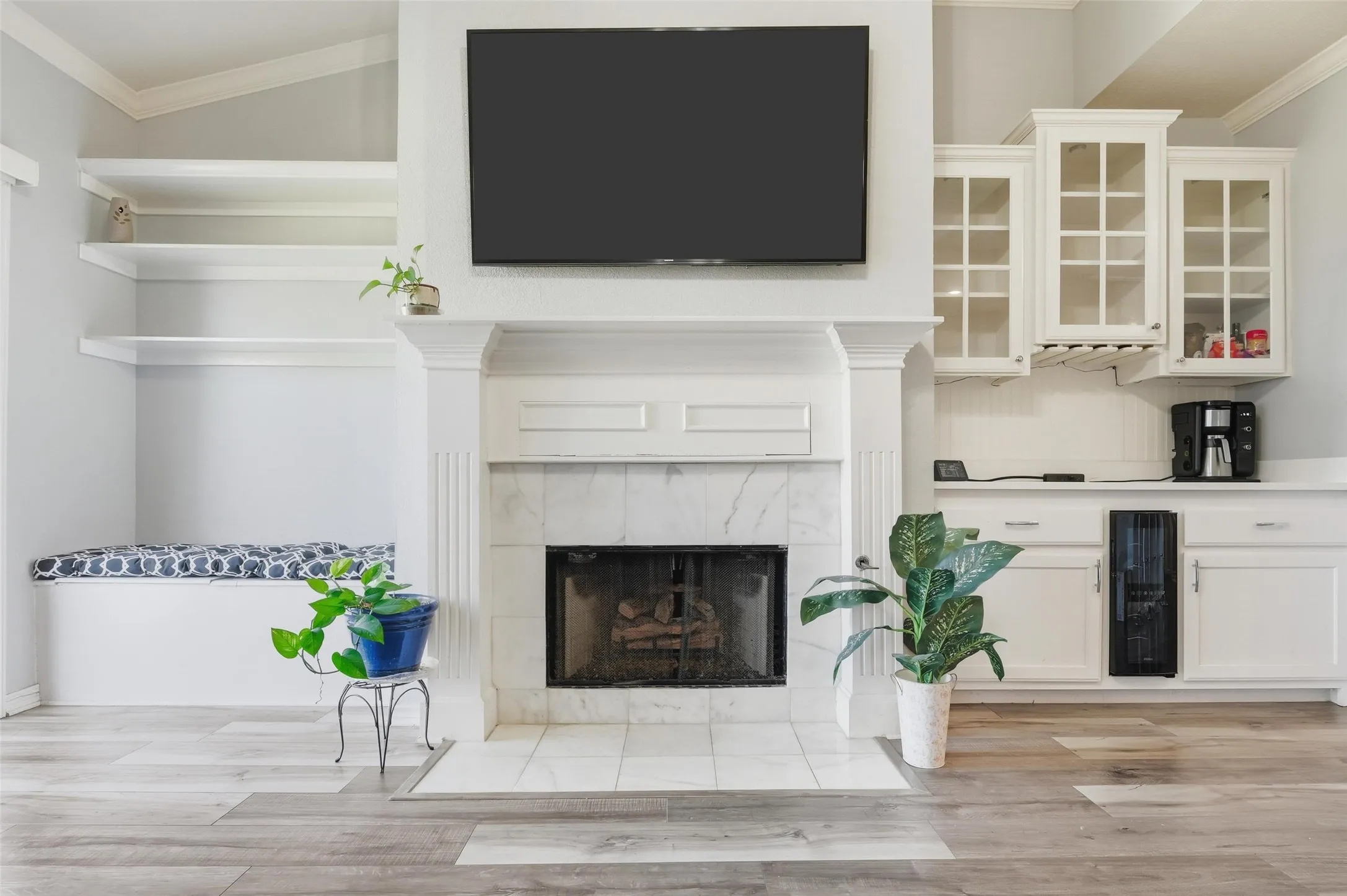 Unfurnished living room with ornamental molding, beverage cooler, light wood-style flooring, and a tiled fireplace