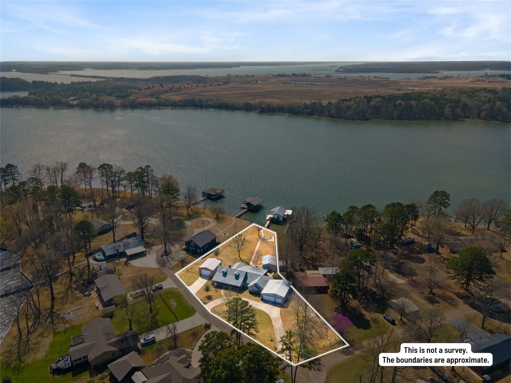 Waterfront property with multiple boat docks, a large residential structure, and mature trees