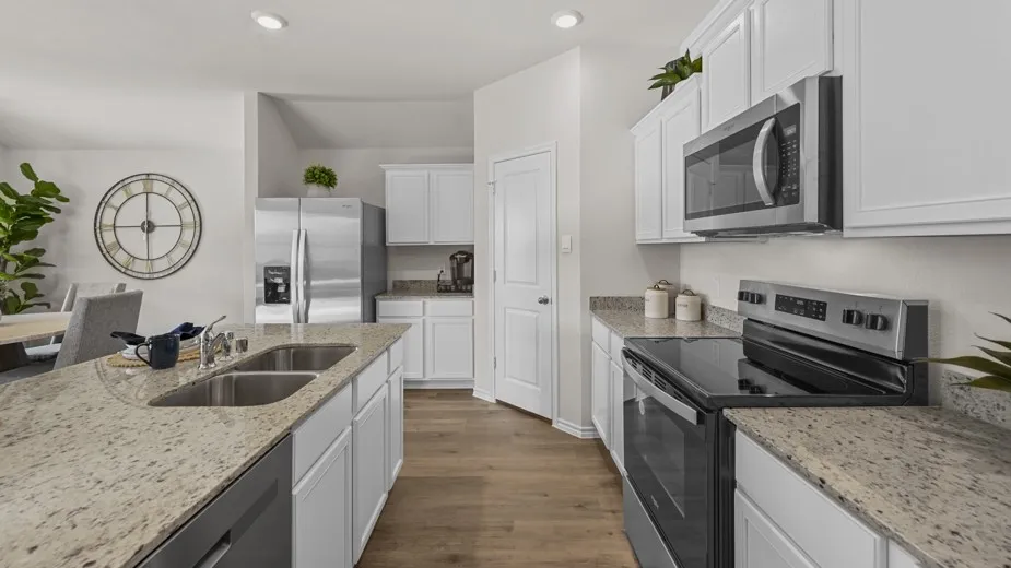 Kitchen with stainless steel appliances, white cabinetry, dark wood-style flooring, light stone counters, and recessed lighting