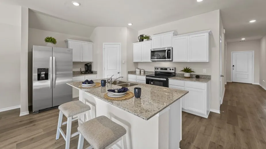 Kitchen featuring stainless steel appliances, white cabinetry, a breakfast bar, light wood finished floors, and recessed lighting