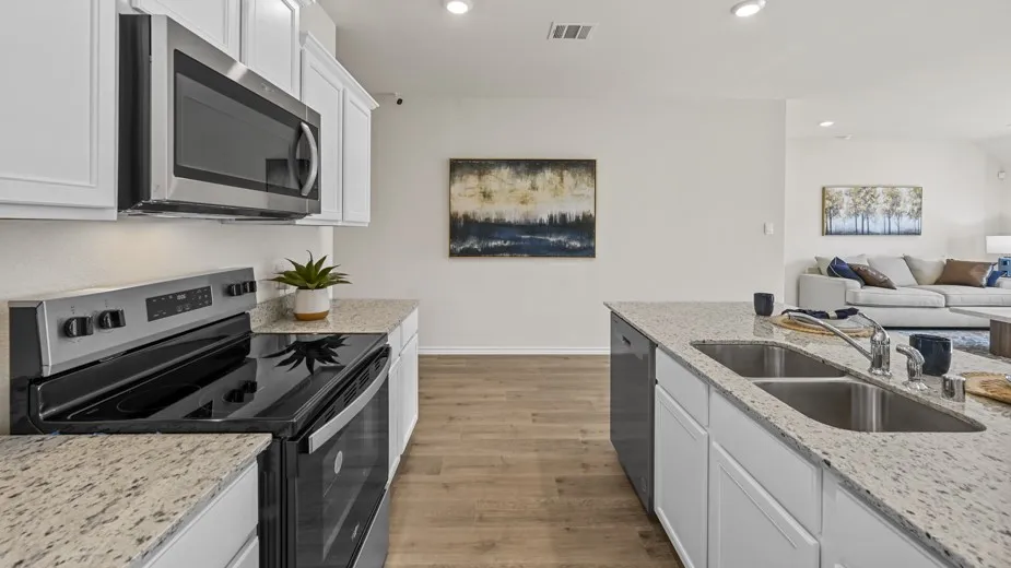 Kitchen featuring stainless steel appliances, white cabinetry, open floor plan, light stone counters, and recessed lighting