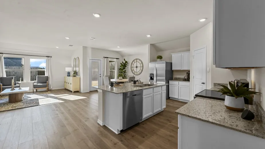 Kitchen featuring light stone counters, stainless steel dishwasher, a center island with sink, recessed lighting, and dark wood-style floors