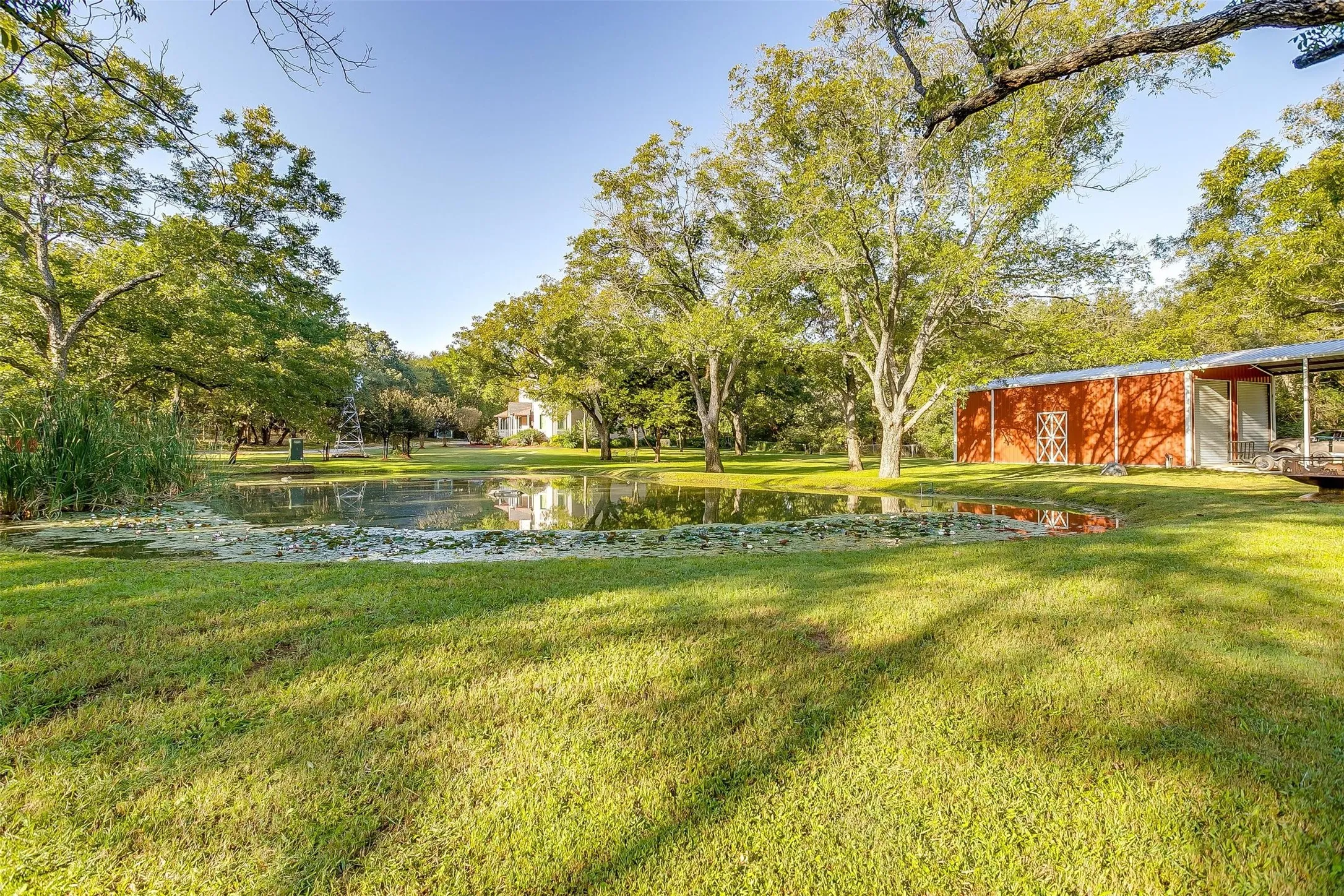 View of grassy yard with a water view, carport and garage