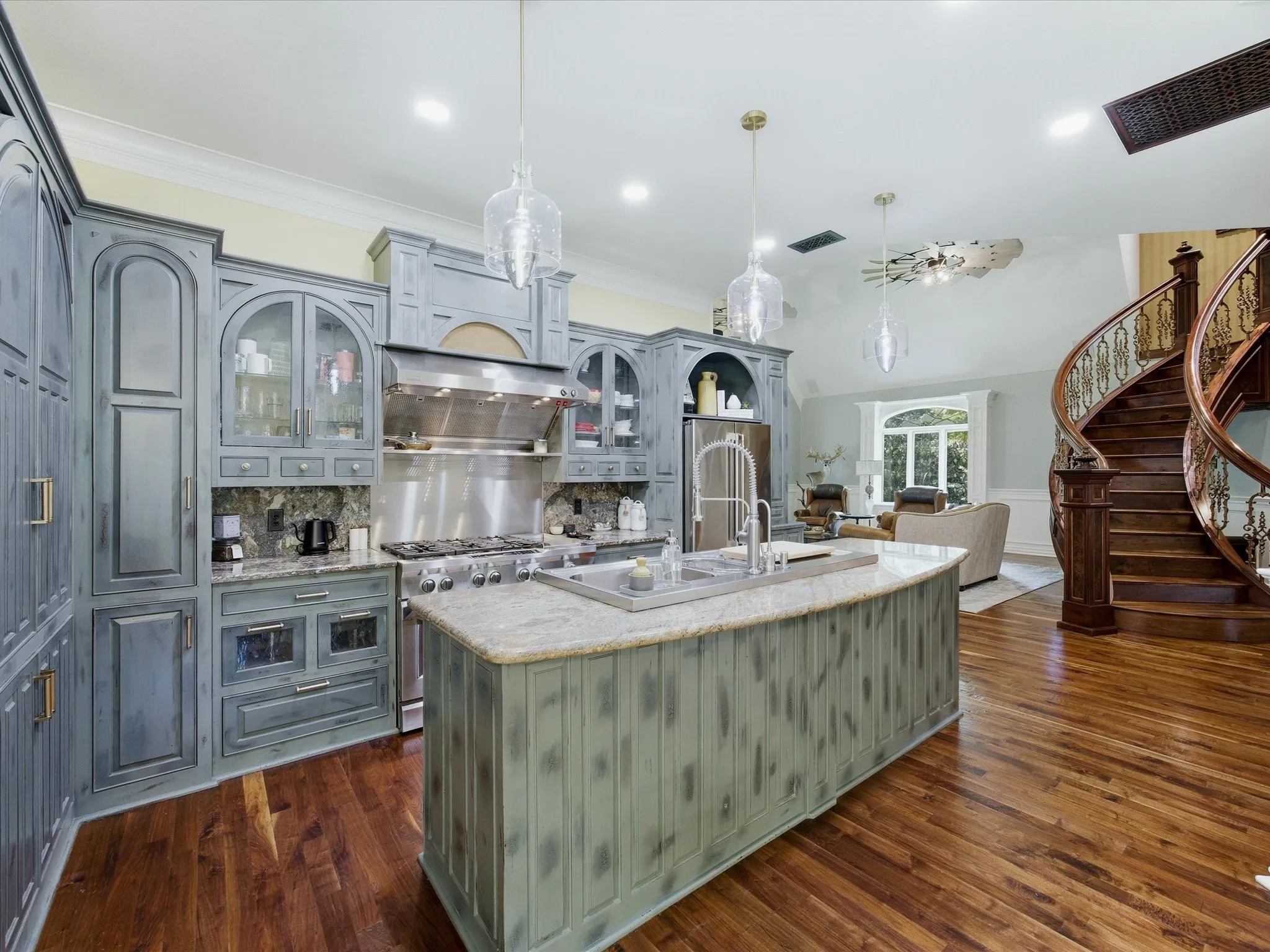 Kitchen featuring distressed cabinetry, stainless steel appliances, granite countertops, and a central island with an undermount sink
