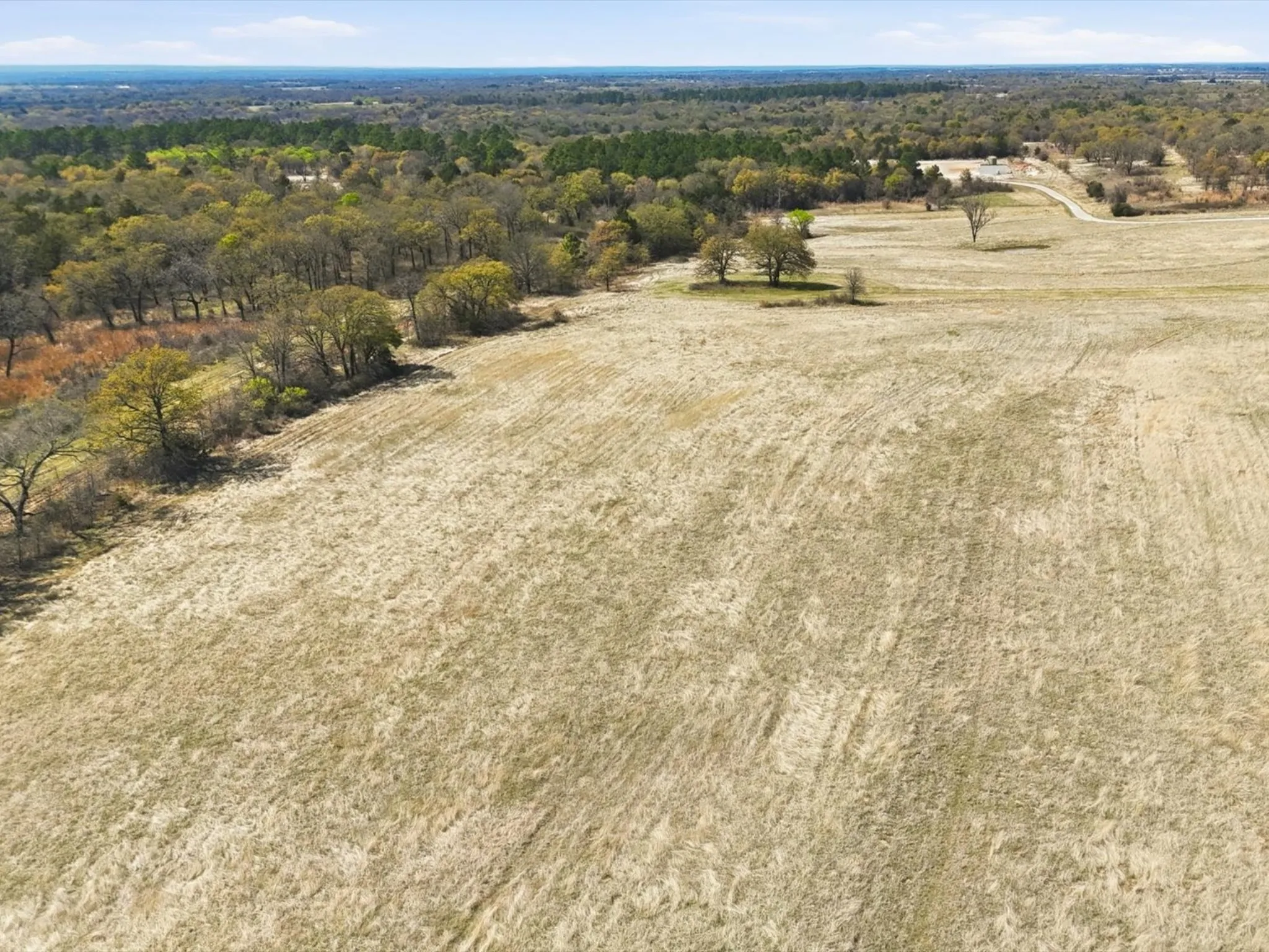 Pasture with 1 of 2 stock tanks on property, fencing, and LBJ National Grasslands beyond