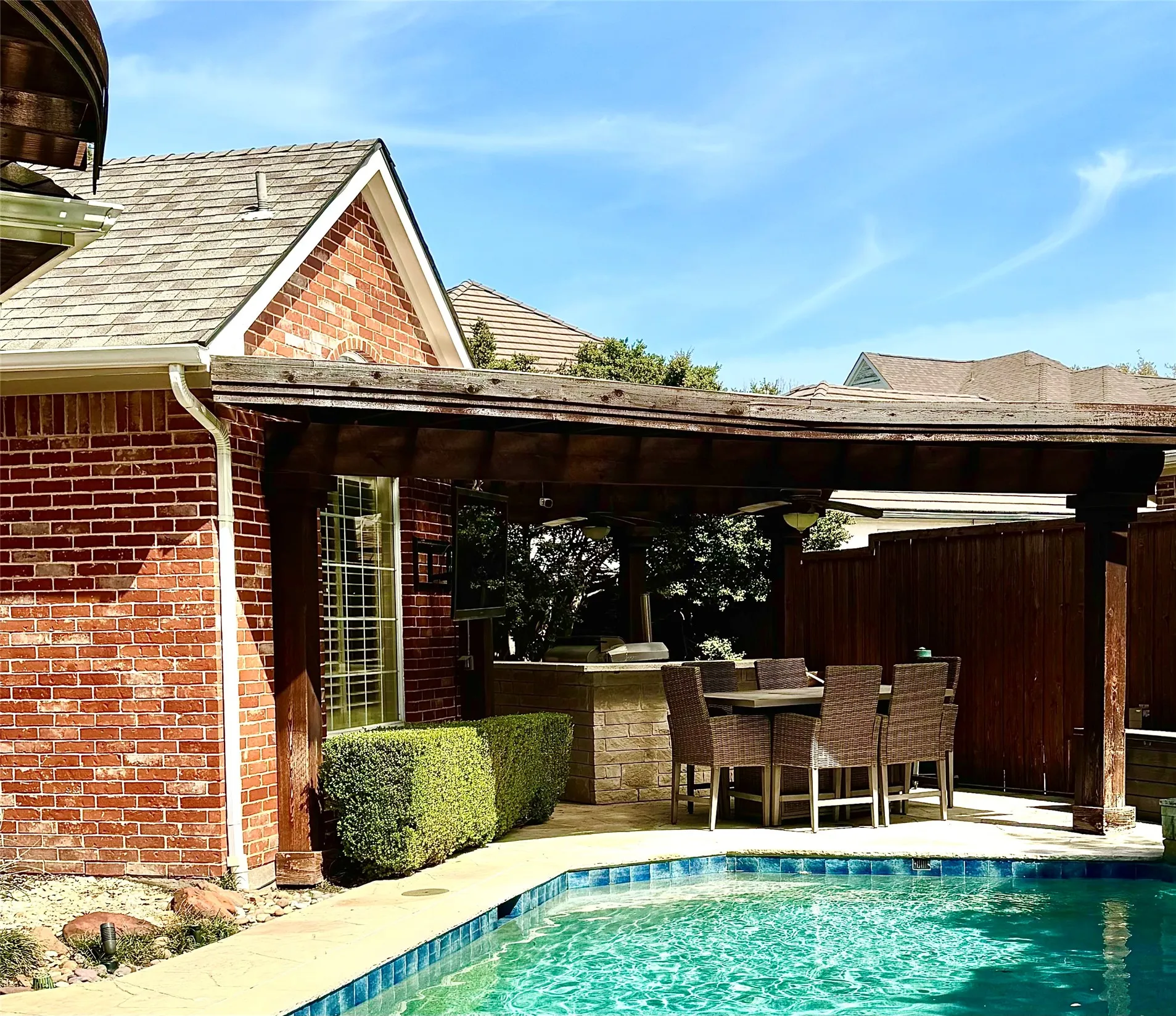 Covered outdoor kitchen with gas grill, green egg and refrigerator.