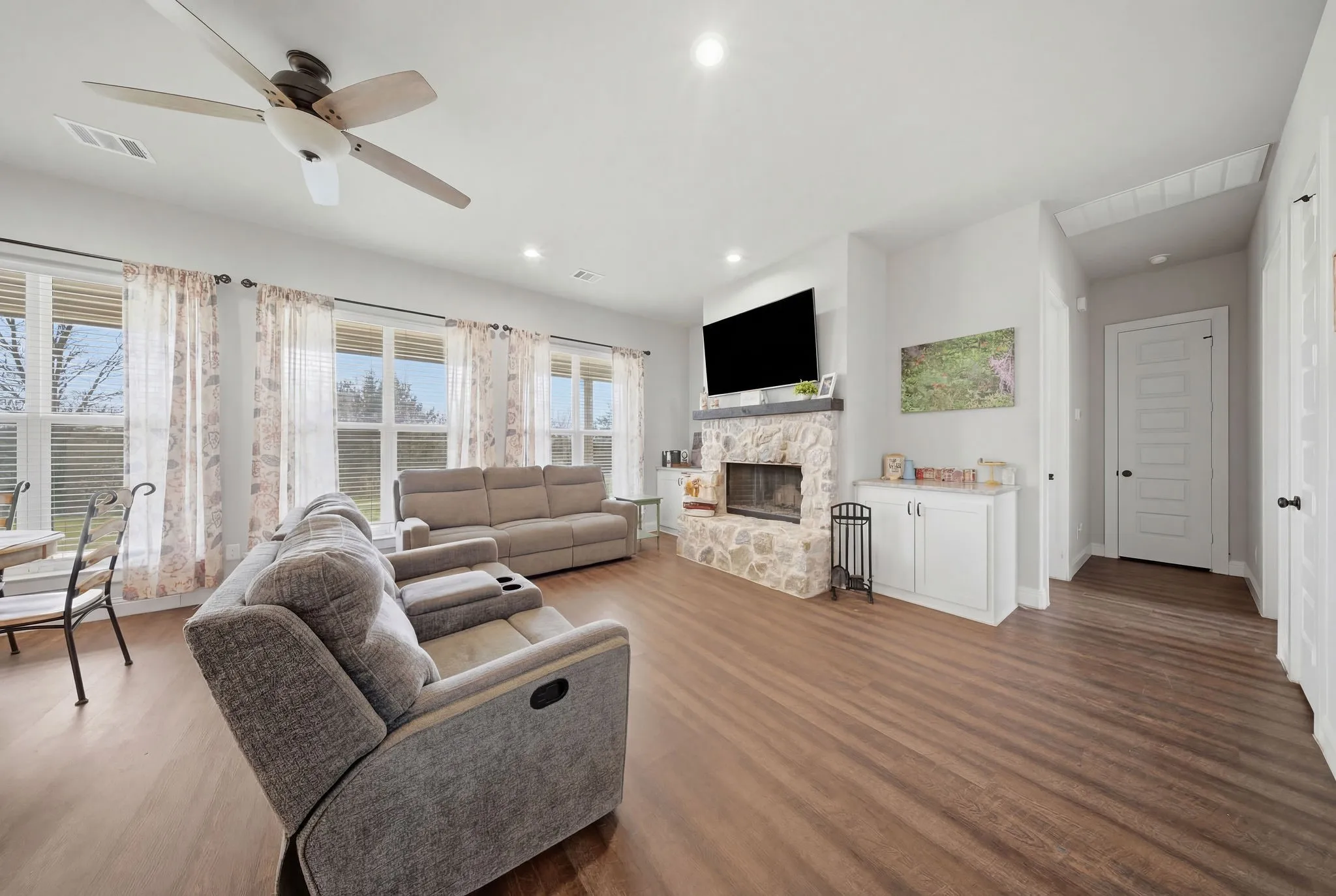 Living room with wood finished floors, ceiling fan, and a fireplace