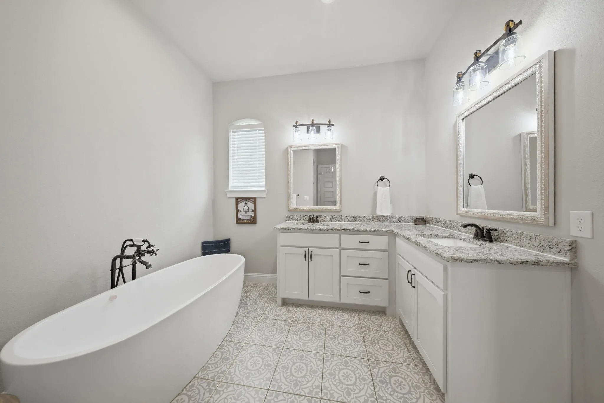 Bathroom featuring double vanity, a soaking tub, and light tile patterned floors