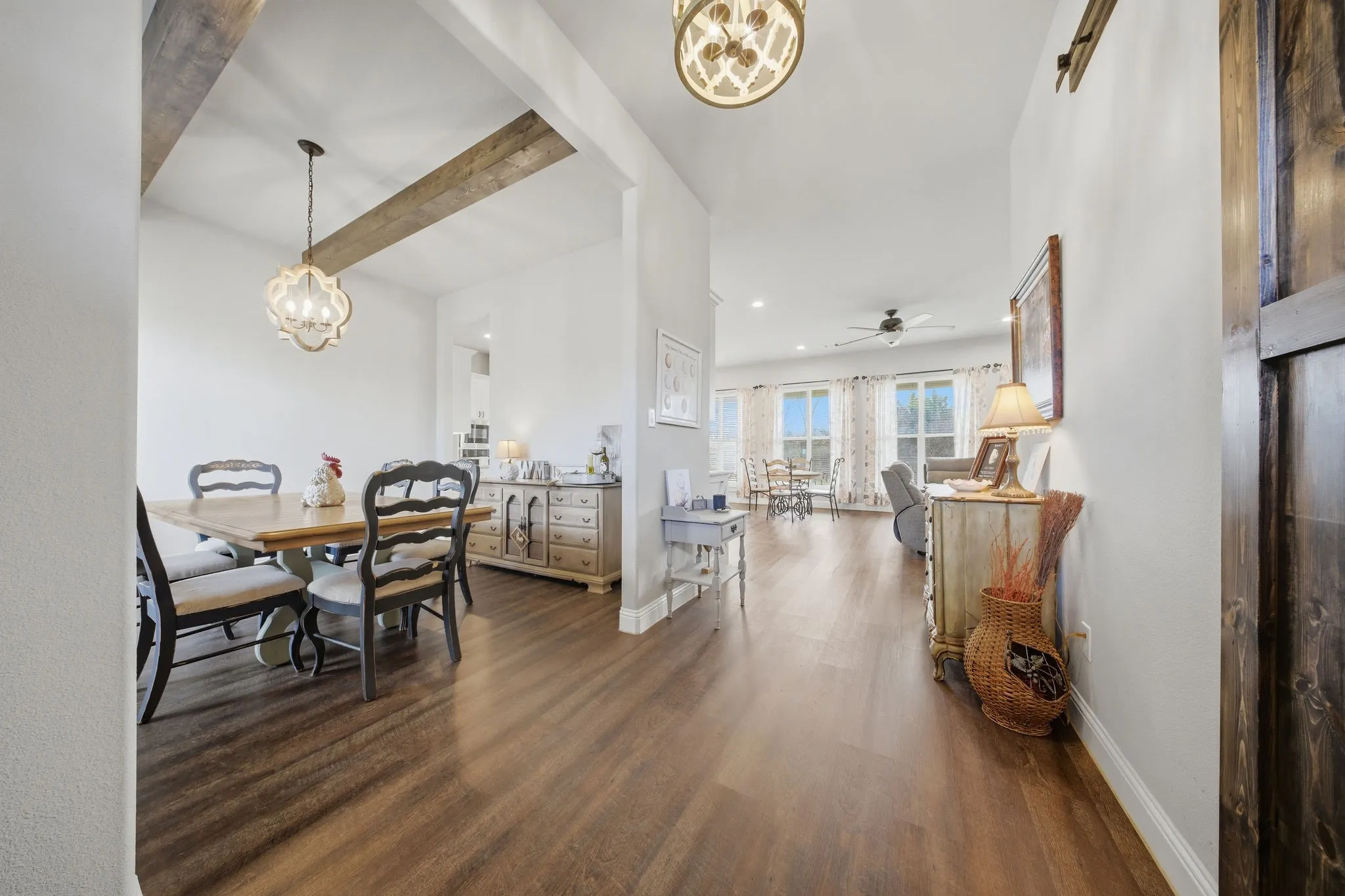 Dining area featuring suspended lighting, dark wood-type flooring, beamed ceiling, and ceiling fan