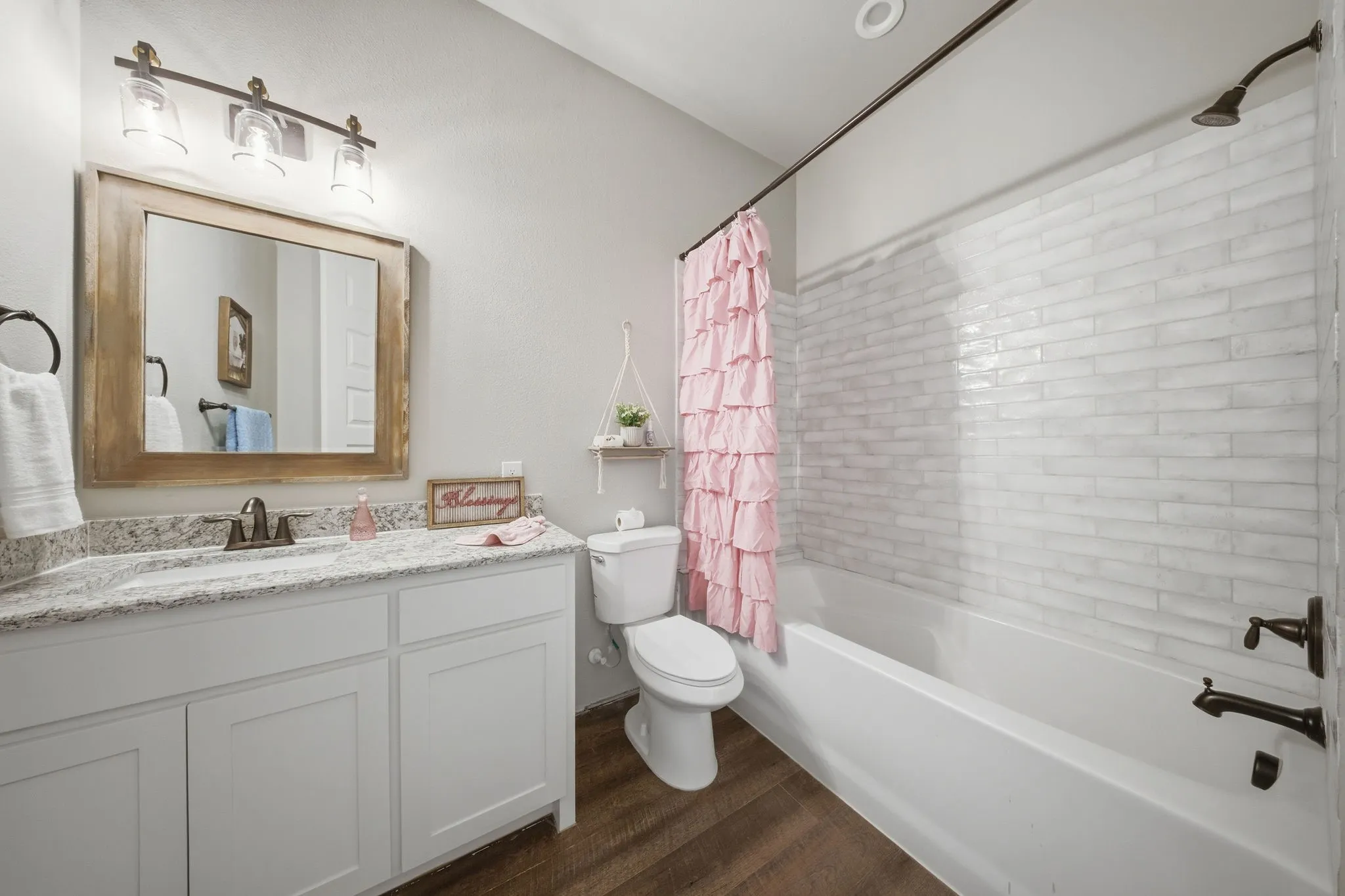 Bathroom with vanity, shower / bath combination with curtain, and dark wood-style floors