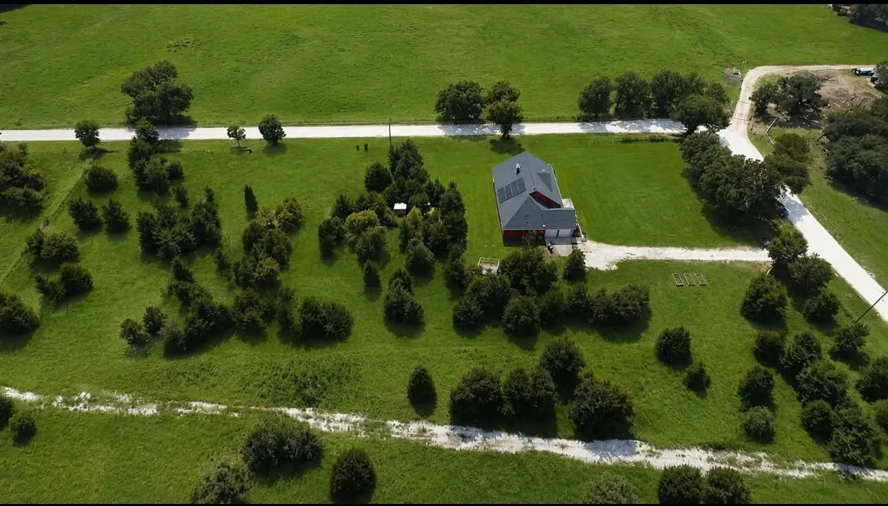 Expansive green landscape featuring a central residence with a dark roof and solar panels