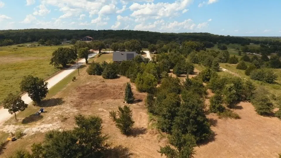 Expansive property featuring a gravel driveway, mature trees, and natural landscaping