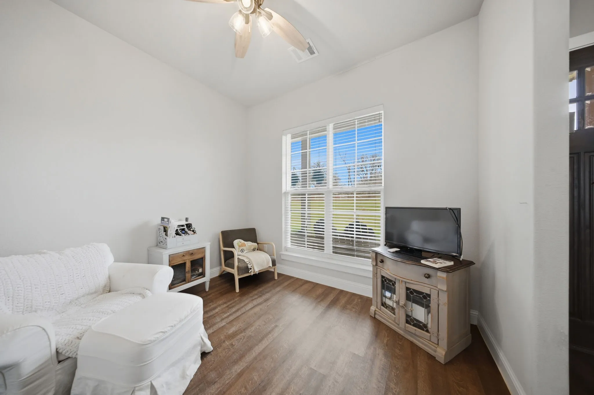 Living area with ceiling fan and dark wood-style flooring