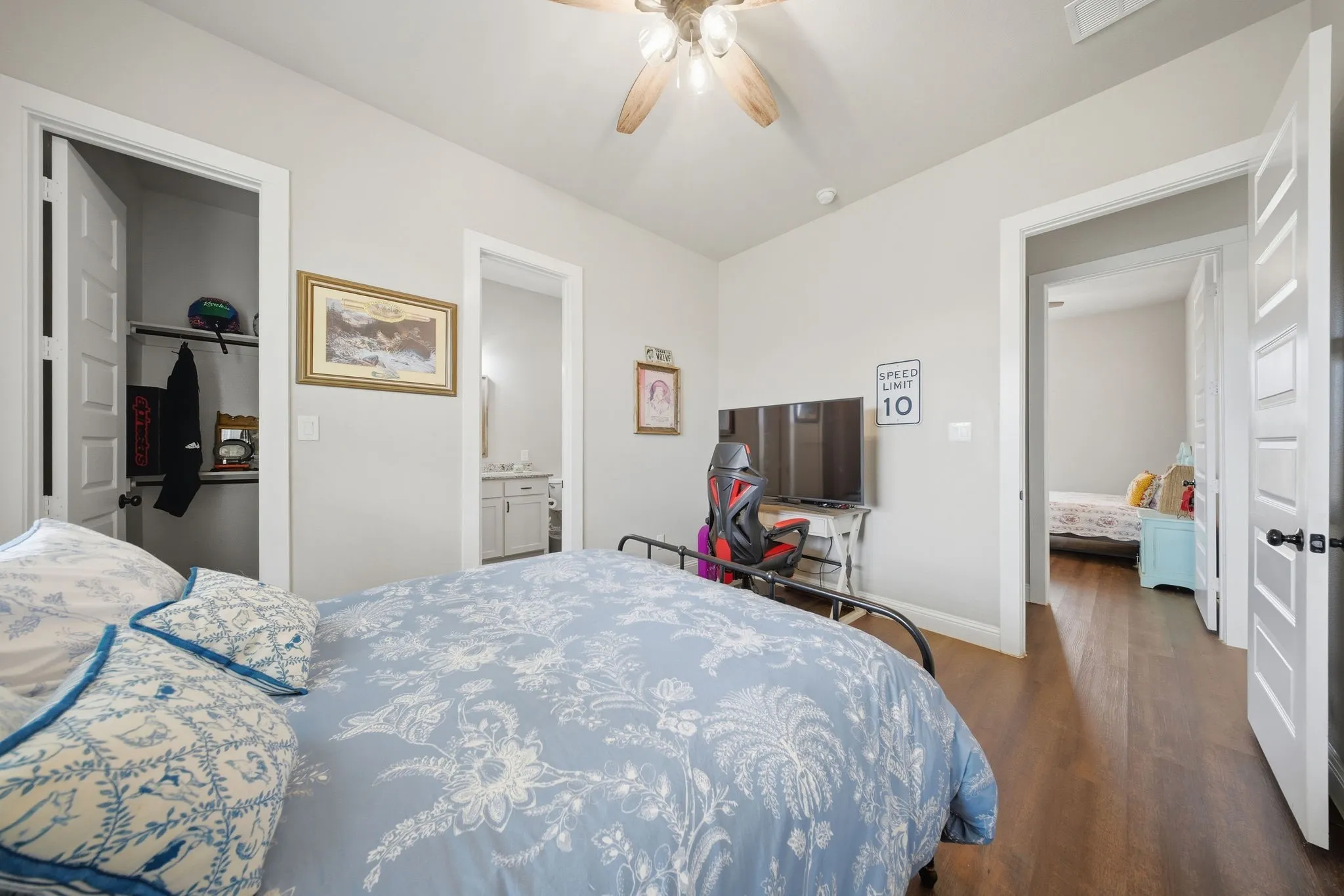 Bedroom with a spacious closet, dark wood-style flooring, ceiling fan, and ensuite bath