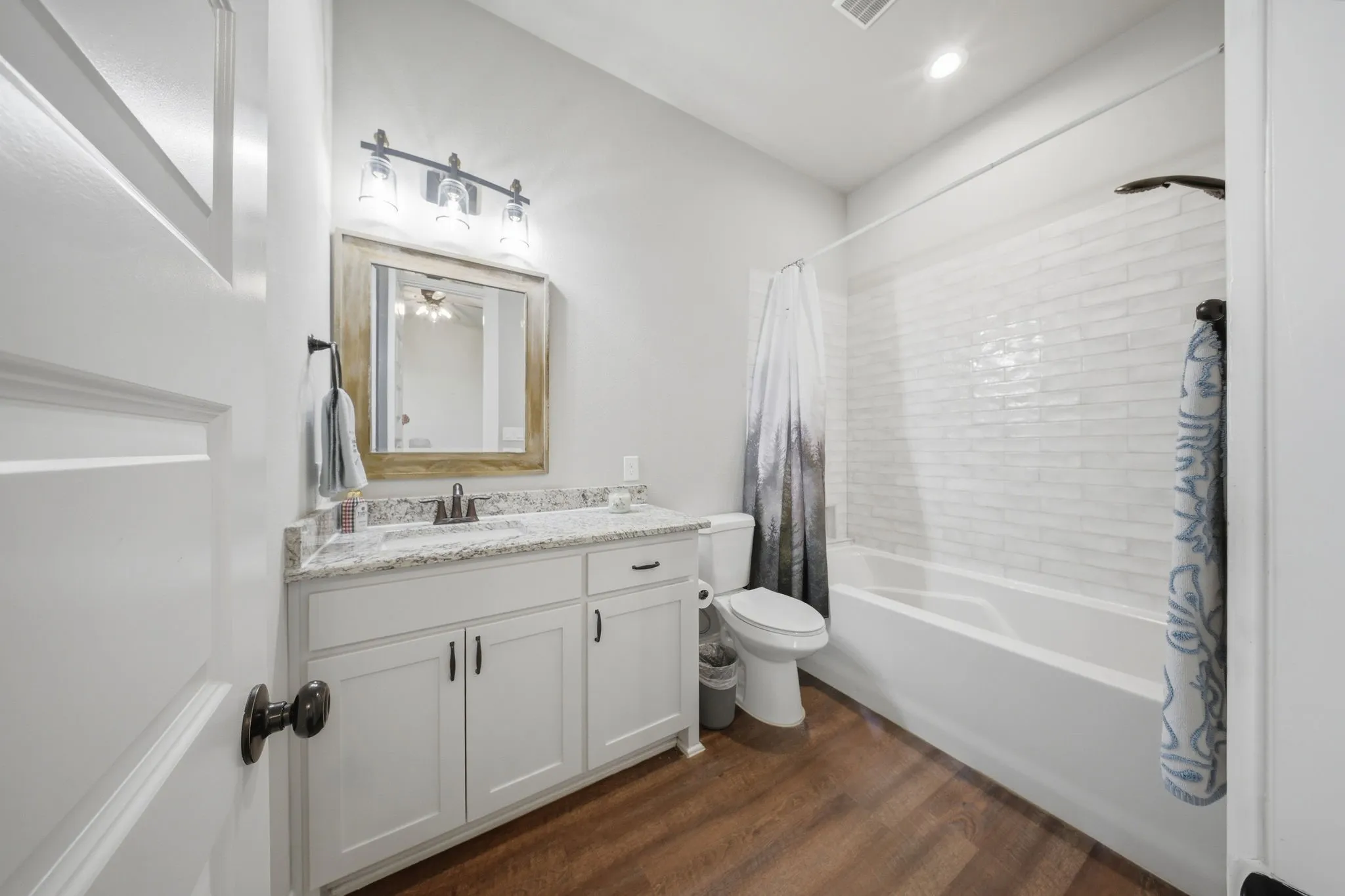 Bathroom with vanity, shower / tub combo with curtain, and dark wood-style flooring