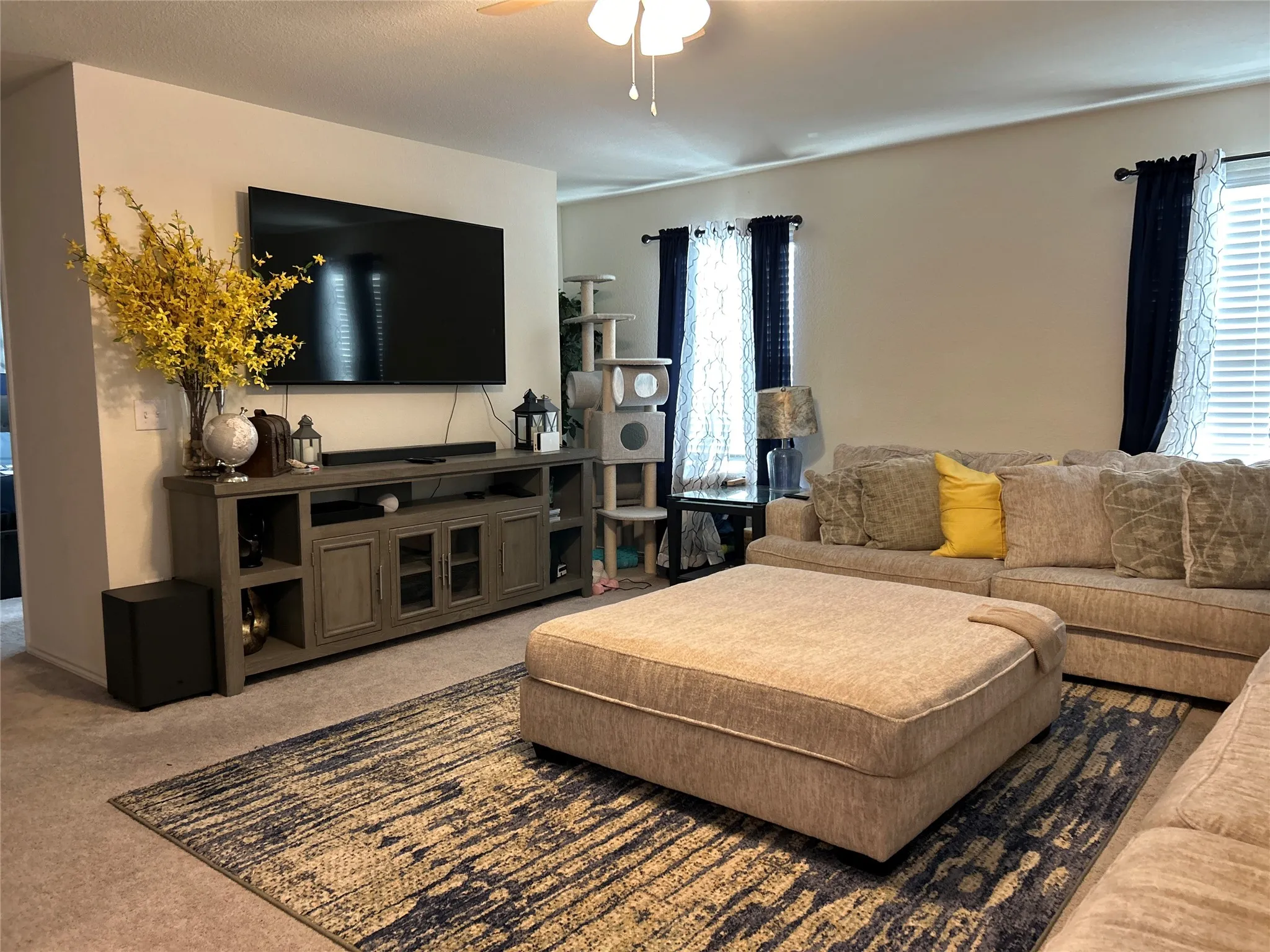 Carpeted living area featuring a ceiling fan