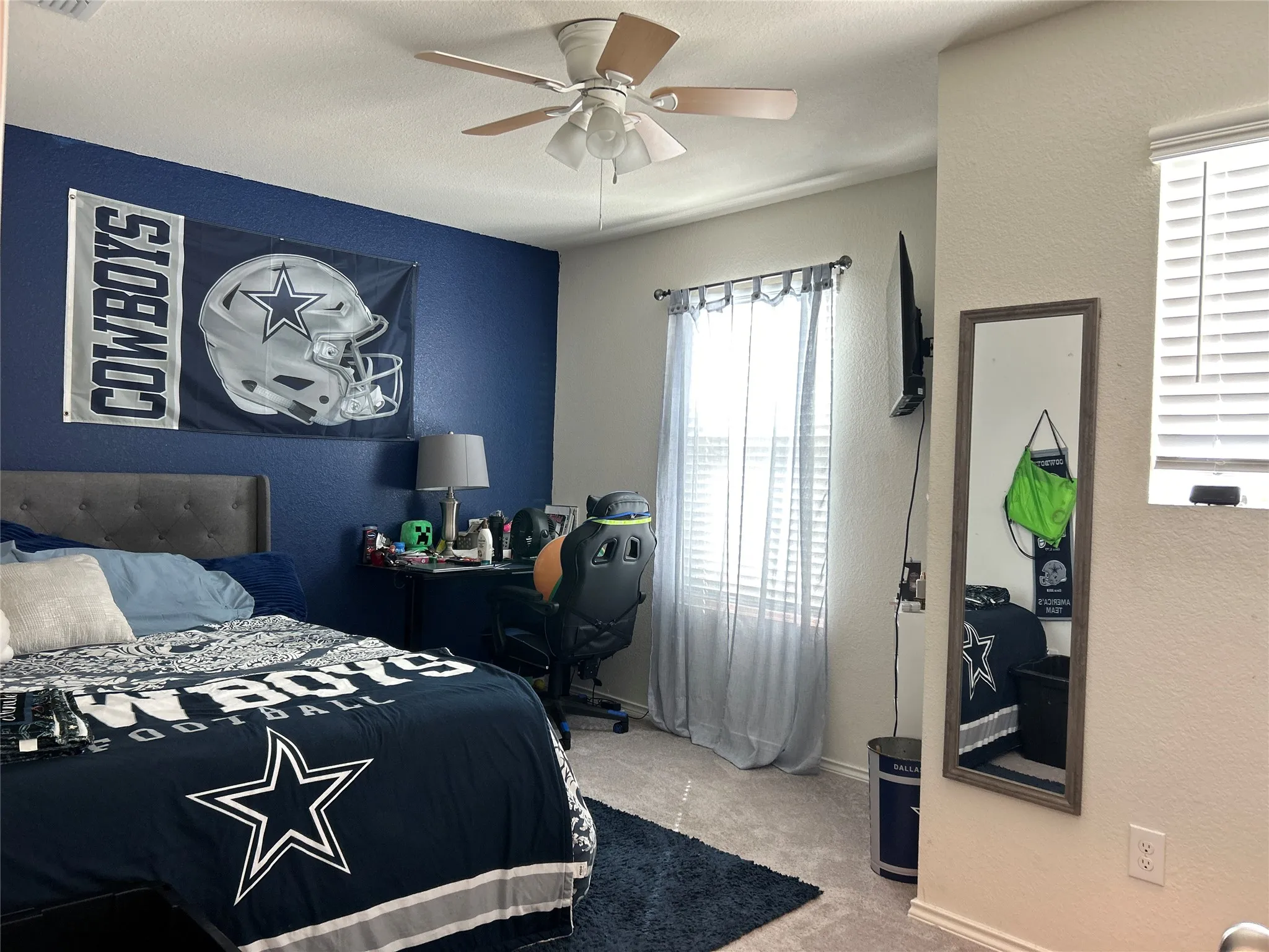 Bedroom with a textured wall, light colored carpet, and a ceiling fan