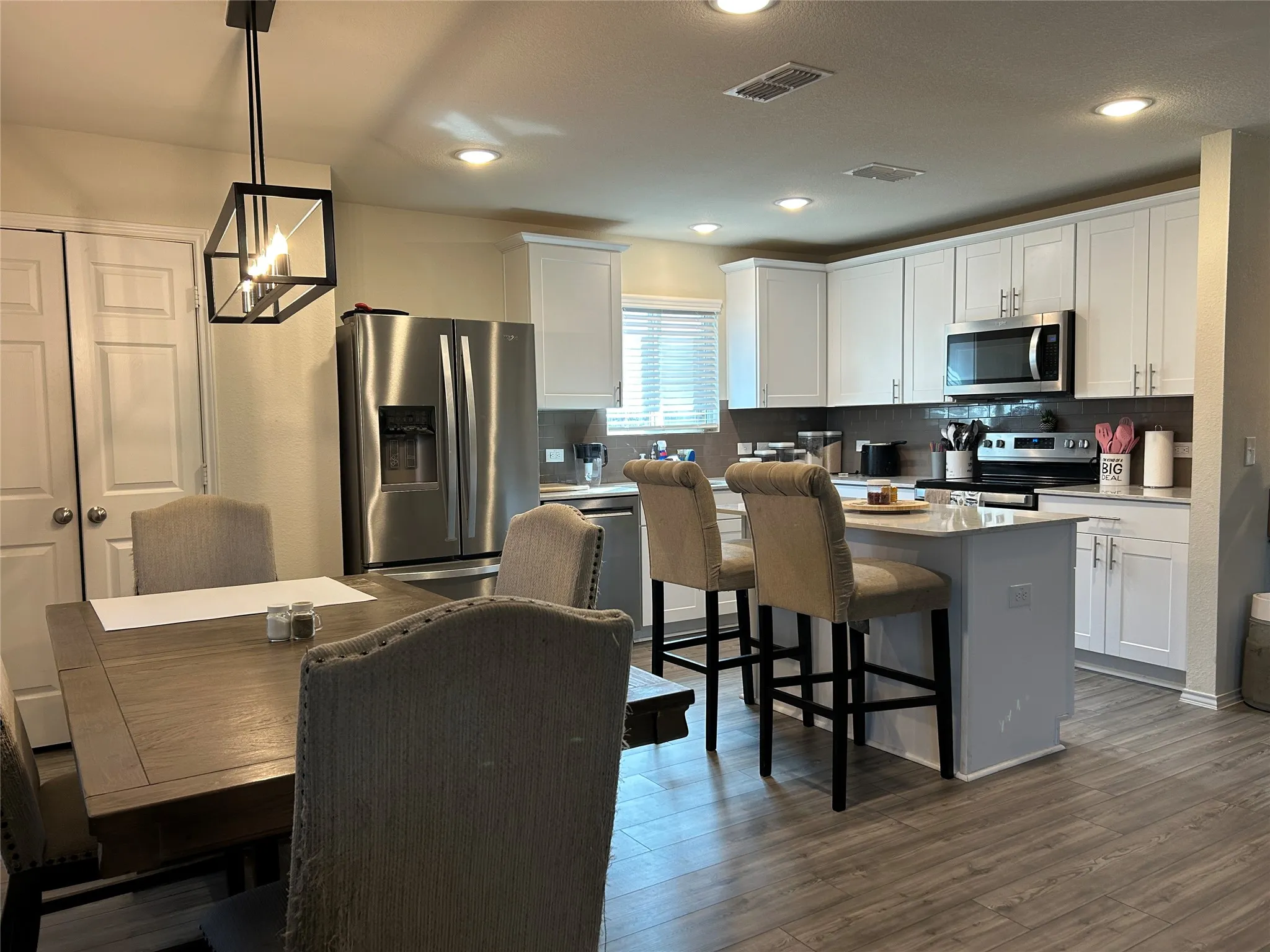 Kitchen featuring stainless steel appliances, a center island, a kitchen breakfast bar, white cabinetry, and dark wood-type flooring