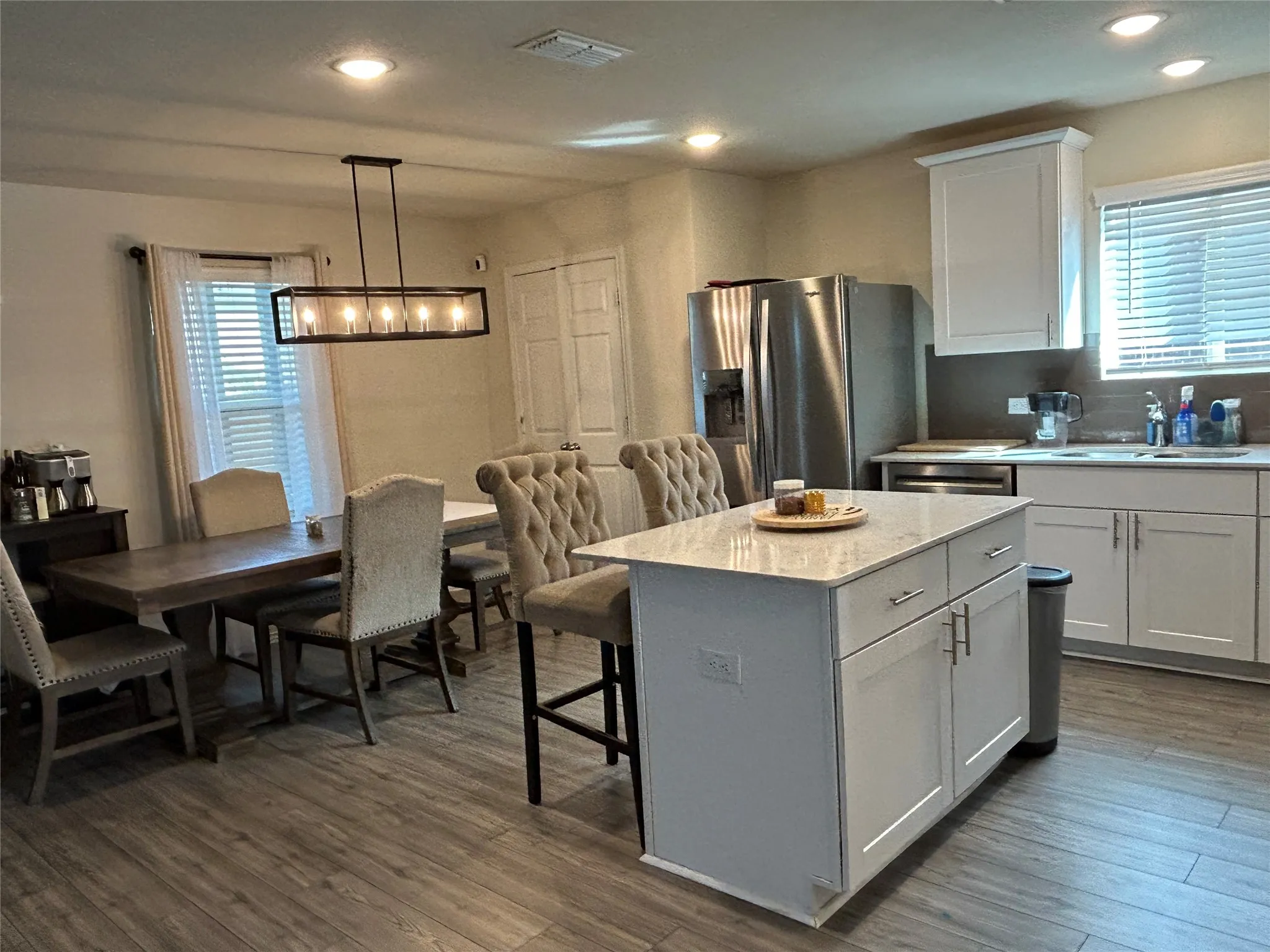 Kitchen featuring healthy amount of natural light, a center island, white cabinets, and hanging light fixtures