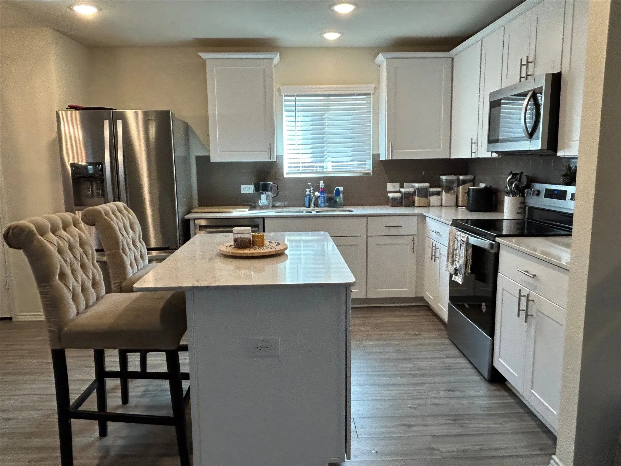 Kitchen with stainless steel appliances, white cabinets, a kitchen breakfast bar, a center island, and recessed lighting