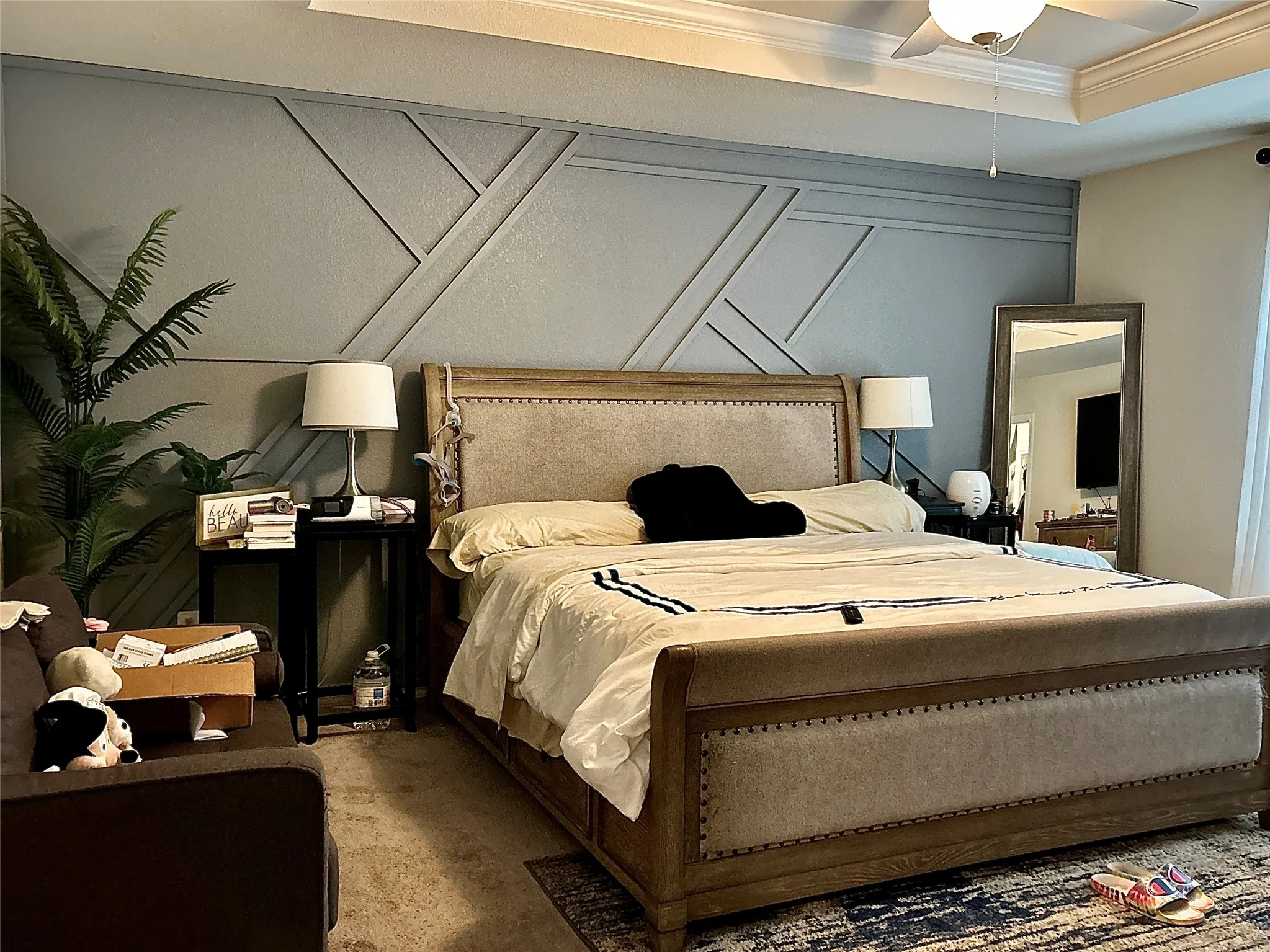 Carpeted Primary   bedroom featuring a decorative wall, ornamental molding, and ceiling fan