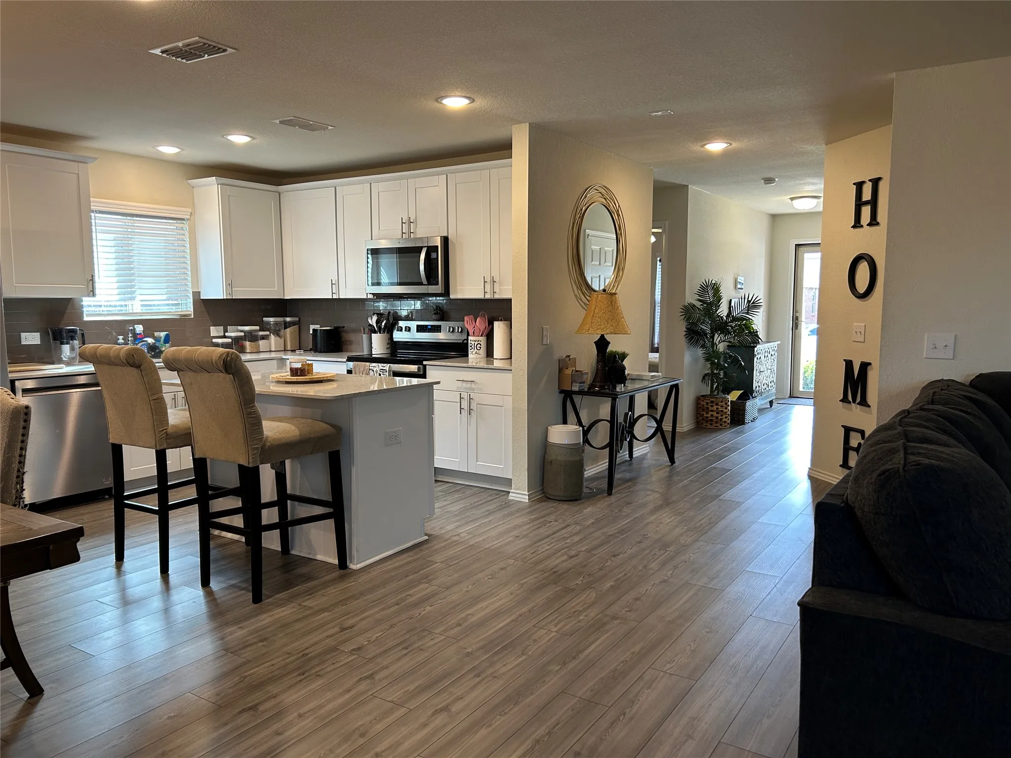 Kitchen featuring a breakfast bar area, stainless steel appliances, white cabinets, open floor plan, and recessed lighting