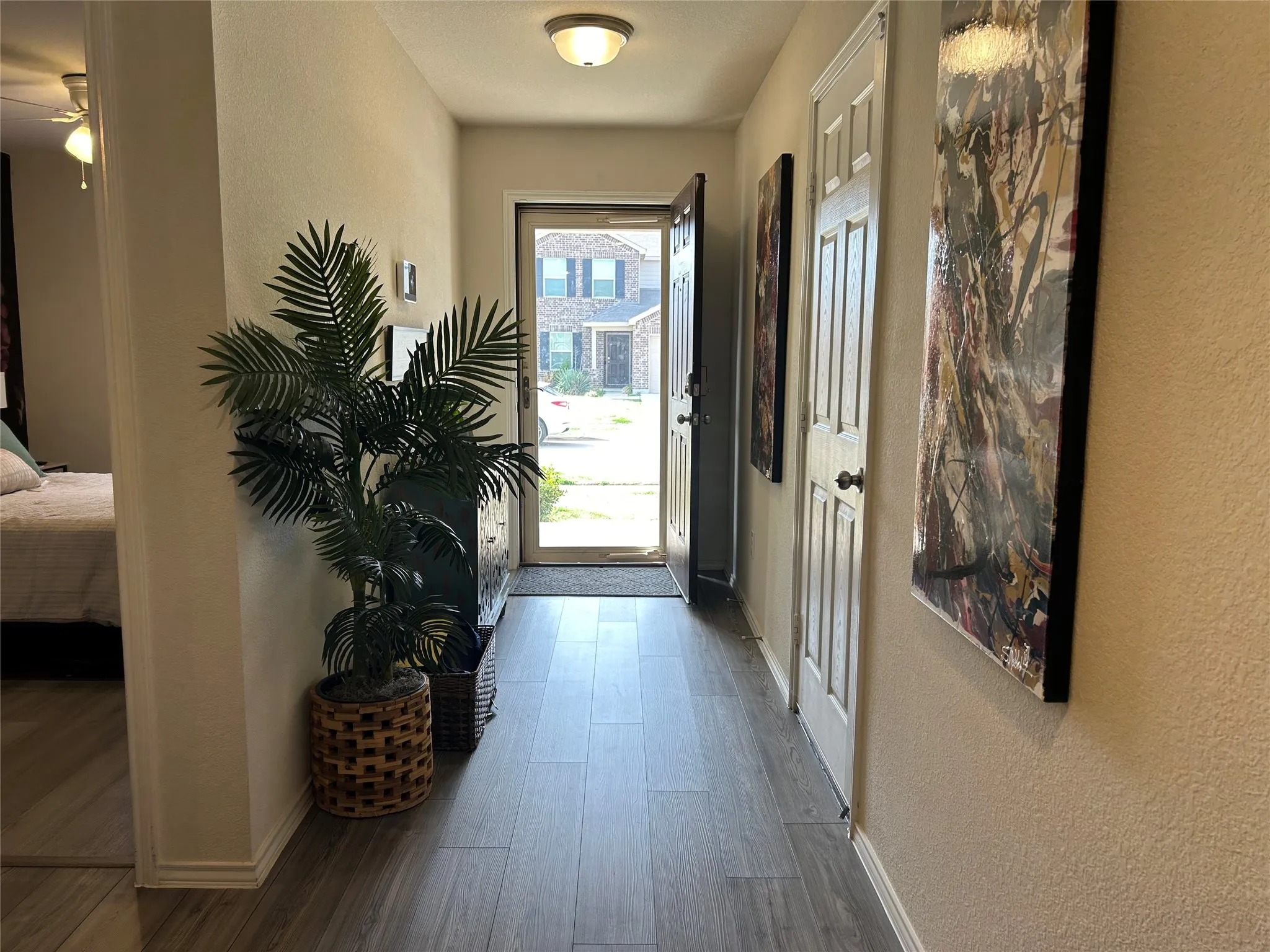 Entrance foyer with a textured wall, dark wood-style flooring, and ceiling fan
