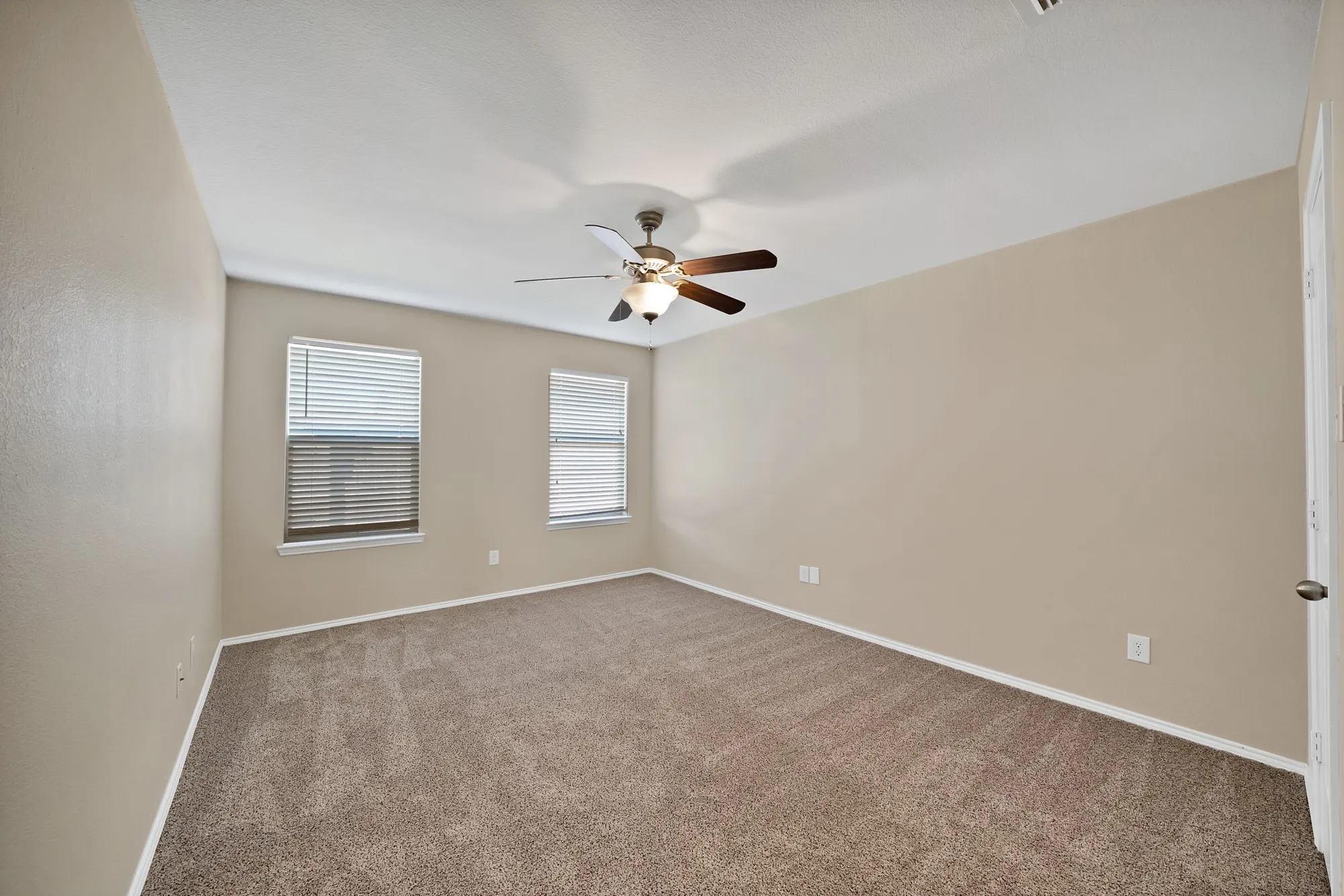 Carpeted spare room featuring baseboards and a ceiling fan