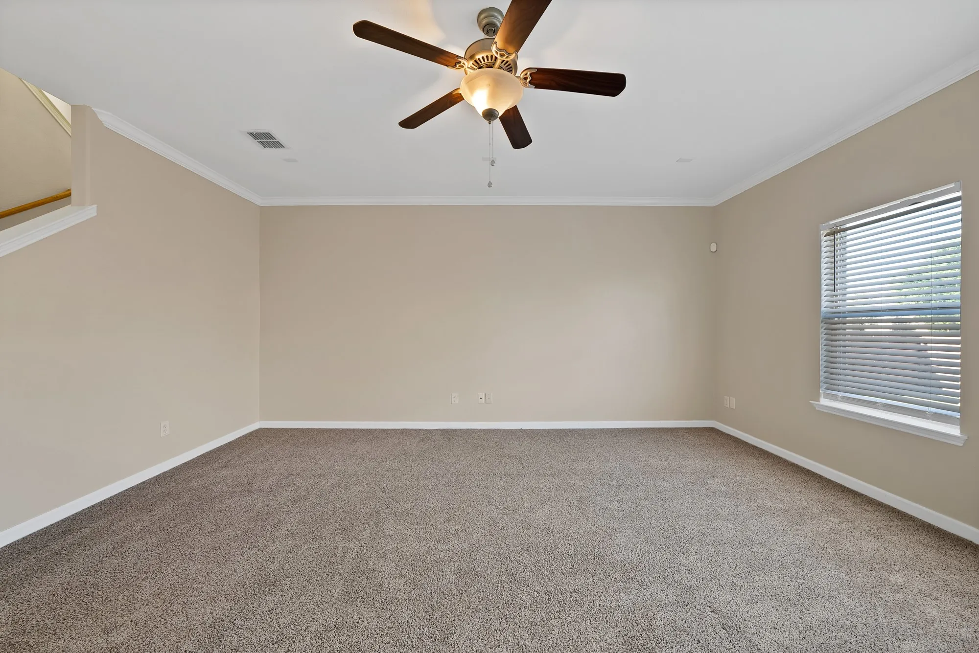 Spare room with ceiling fan, crown molding, and carpet floors
