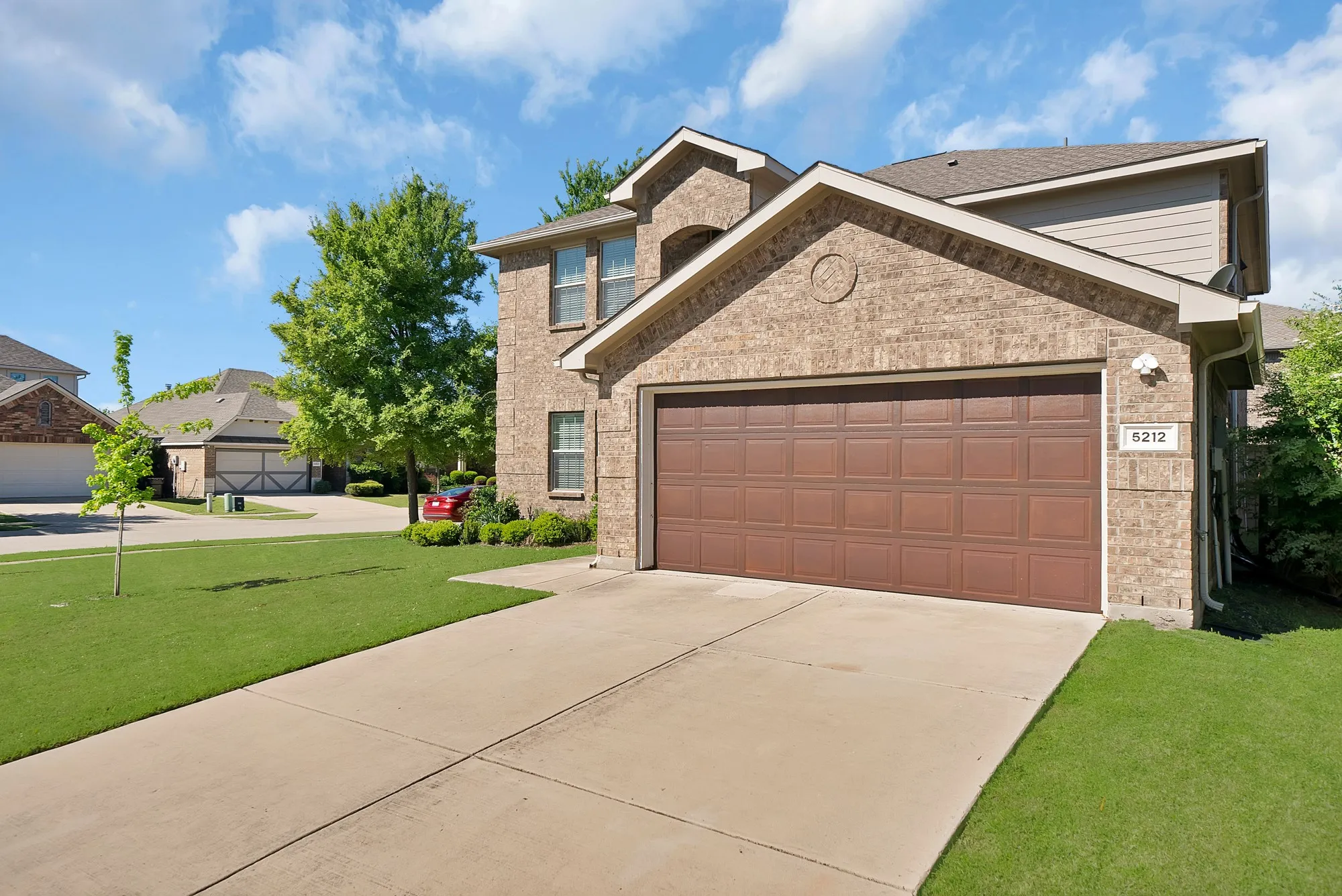 View of front of property featuring an attached garage, a front yard, brick siding, and driveway
