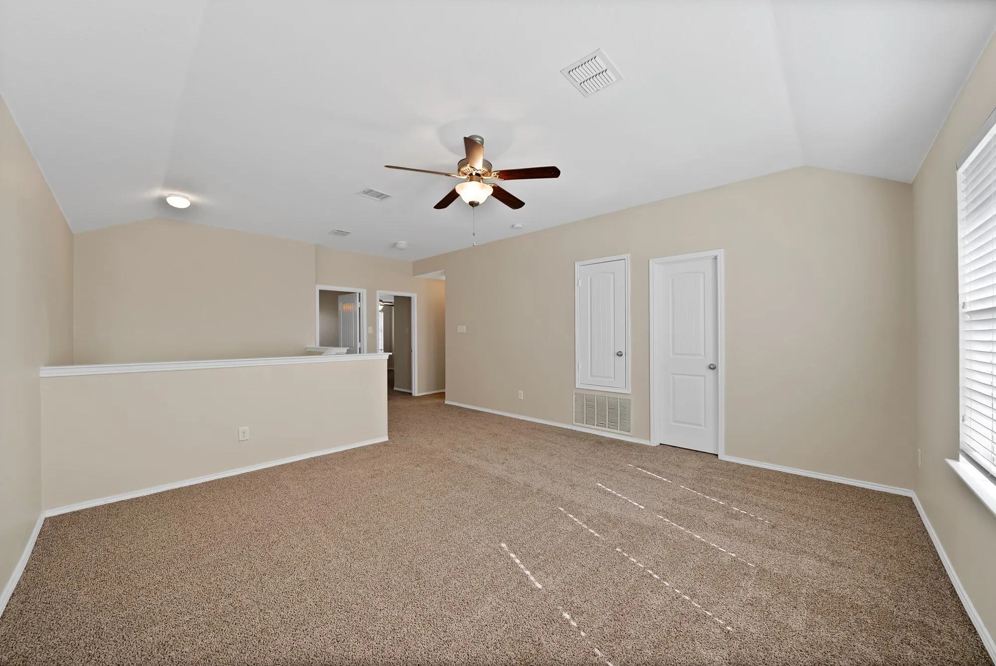 Carpeted spare room featuring lofted ceiling and ceiling fan