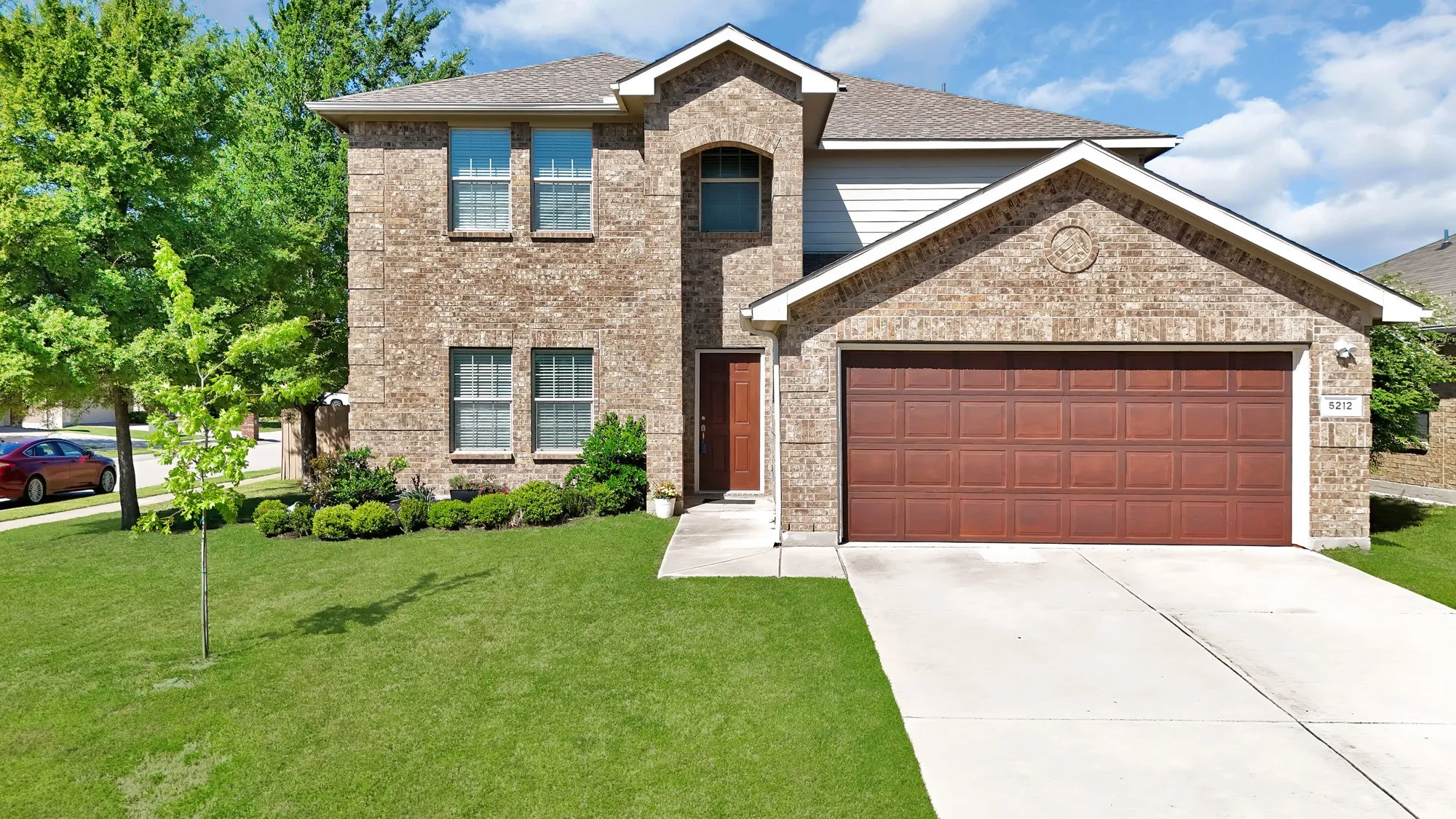 View of front of property with a garage, a front lawn, concrete driveway, and brick siding