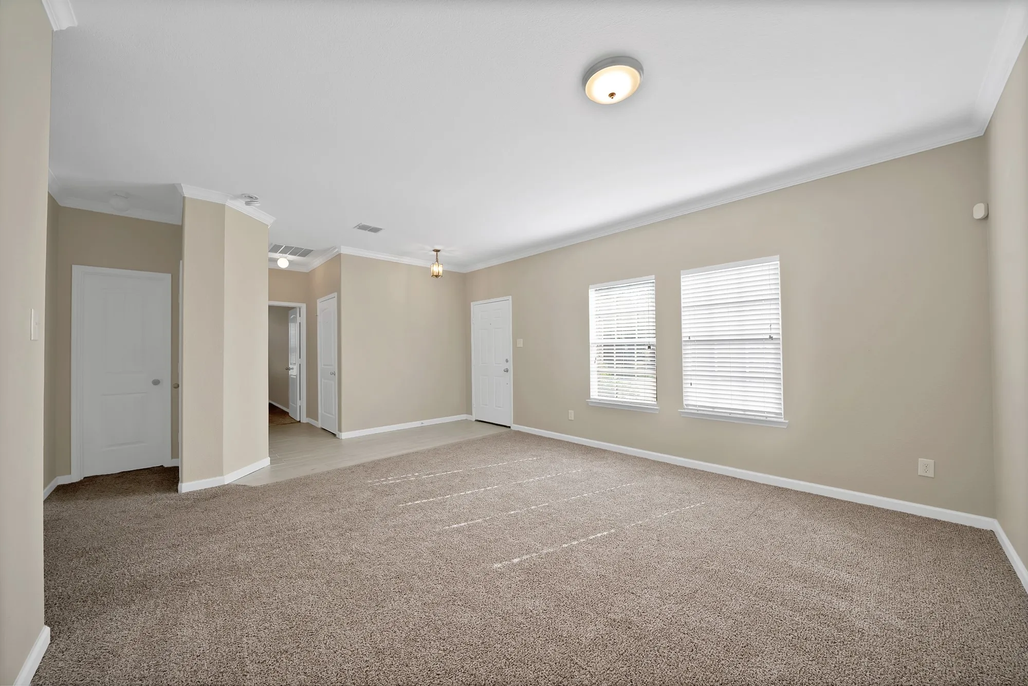 Empty room with ornamental molding and light carpet