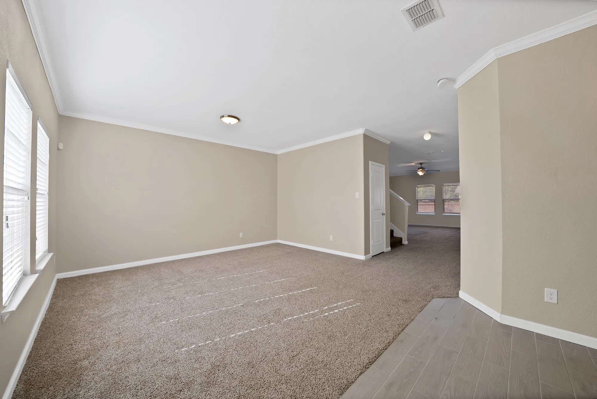 Spare room with crown molding, light colored carpet, and a ceiling fan